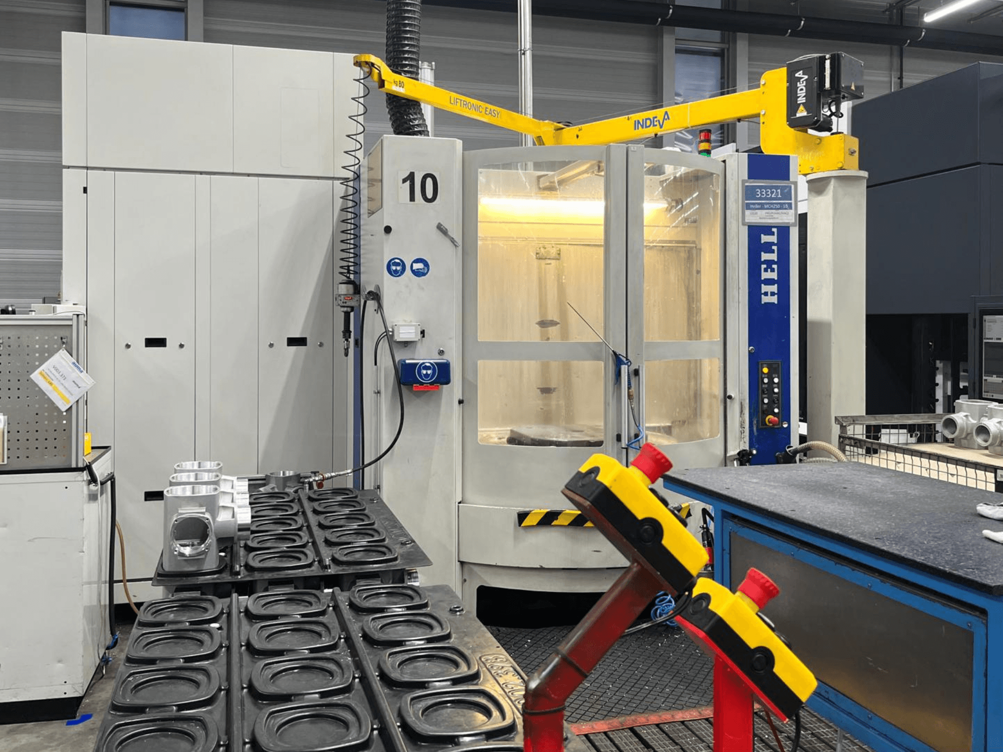 Centro de maquinação horizontal HELLER MCH 250 em vista frontal, com peças de alumínio e botões de controlo visíveis na lateral.