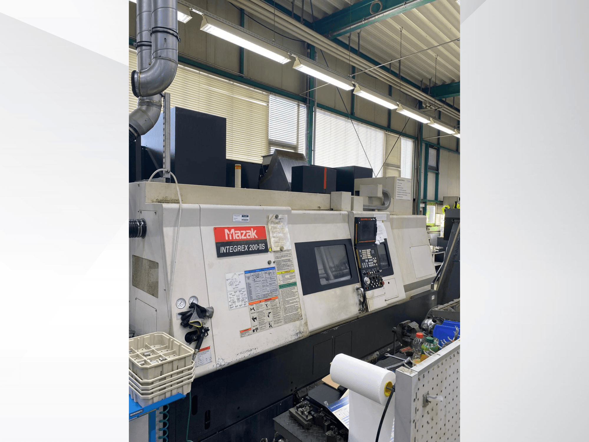 Centro de torneamento e fresagem Mazak INTEGREX 200 III S, vista lateral, mostrando o painel de controlo, os indicadores e as ferramentas da área de trabalho.