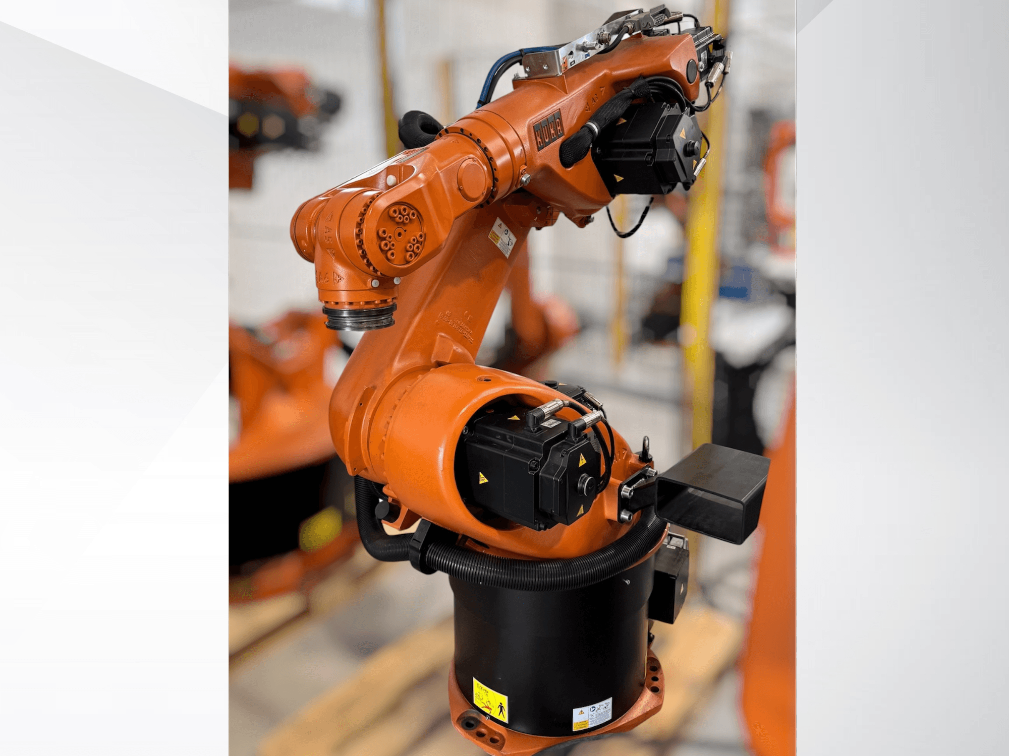 Braço robótico KUKA KR 60-3 em laranja; vista lateral mostrando a base, as articulações e os módulos de controlo para tarefas de automação.