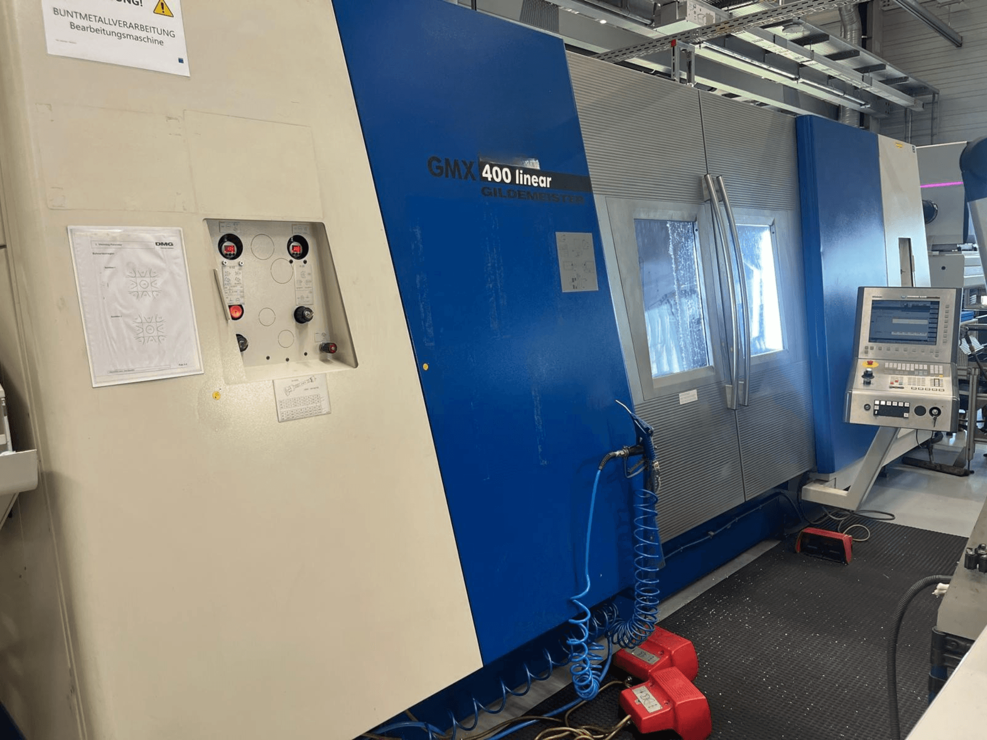 Centro de torneamento e fresagem linear Gildemeister GMX 400, vista frontal que mostra o painel de controlo, o sistema de refrigeração e os botões operacionais.