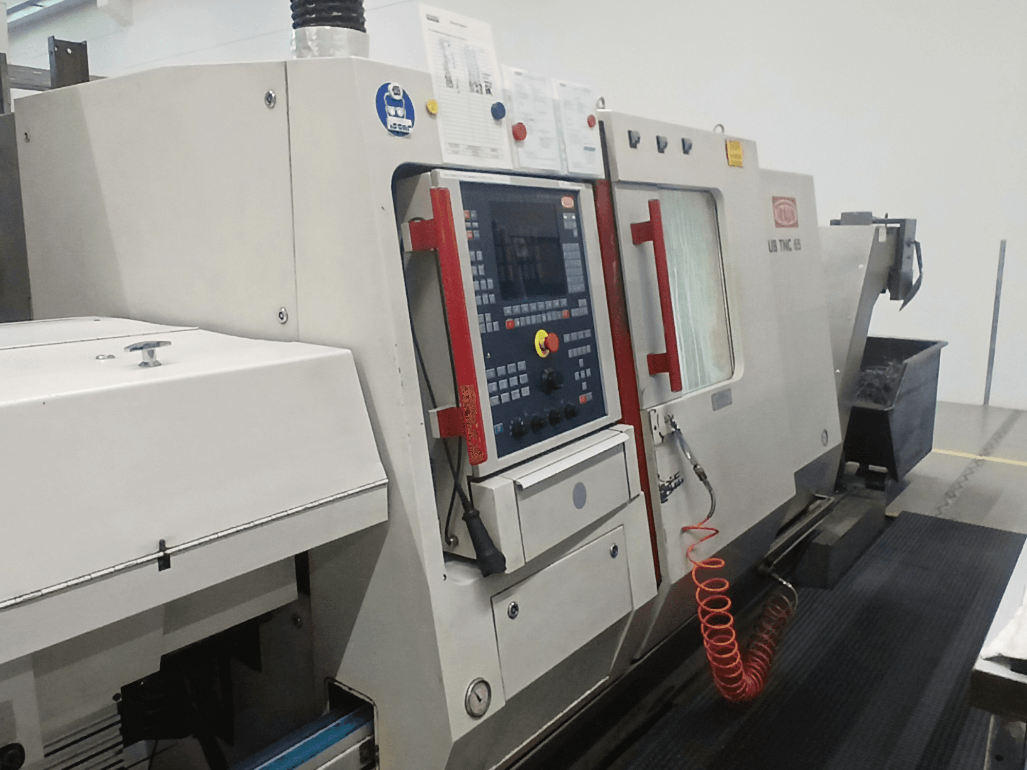 Torneiro horizontal TRAUB TNC65 DG, vista frontal, mostrando o painel de controlo e as ferramentas, ideal para maquinação de precisão.