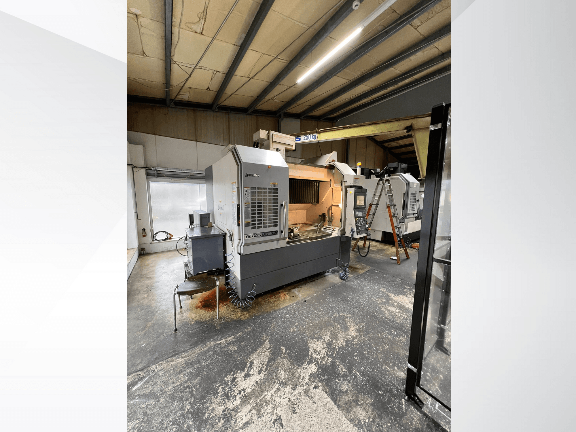 Máquina CNC GRETOS 750 numa oficina, vista frontal, mostrando o painel de controlo e a área de trabalho com ferramentas, escada visível ao fundo.