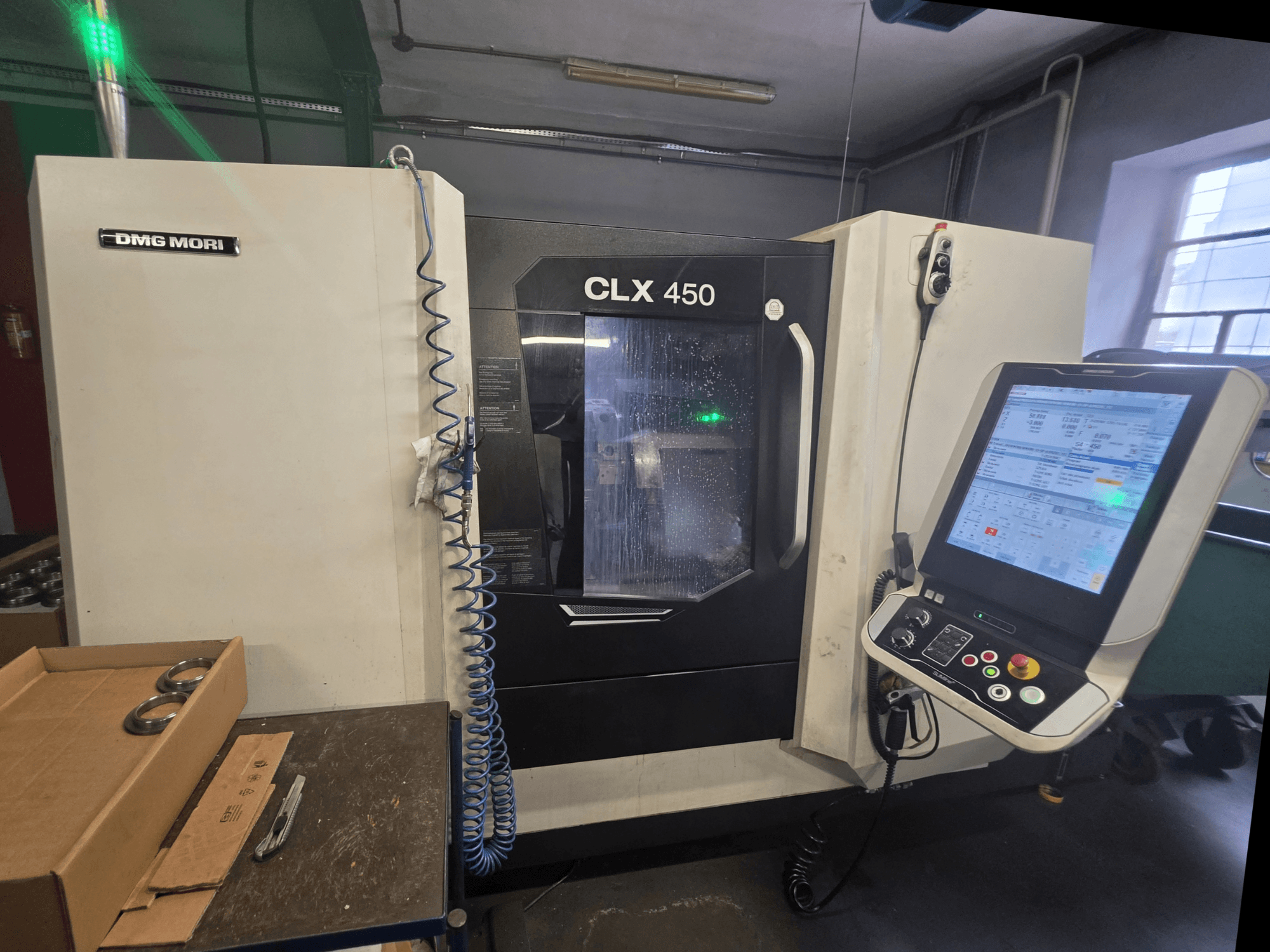 Vista frontal do torno horizontal DMG MORI CLX 450 V3, mostrando o painel de controlo, o sistema de refrigeração e a área de trabalho.