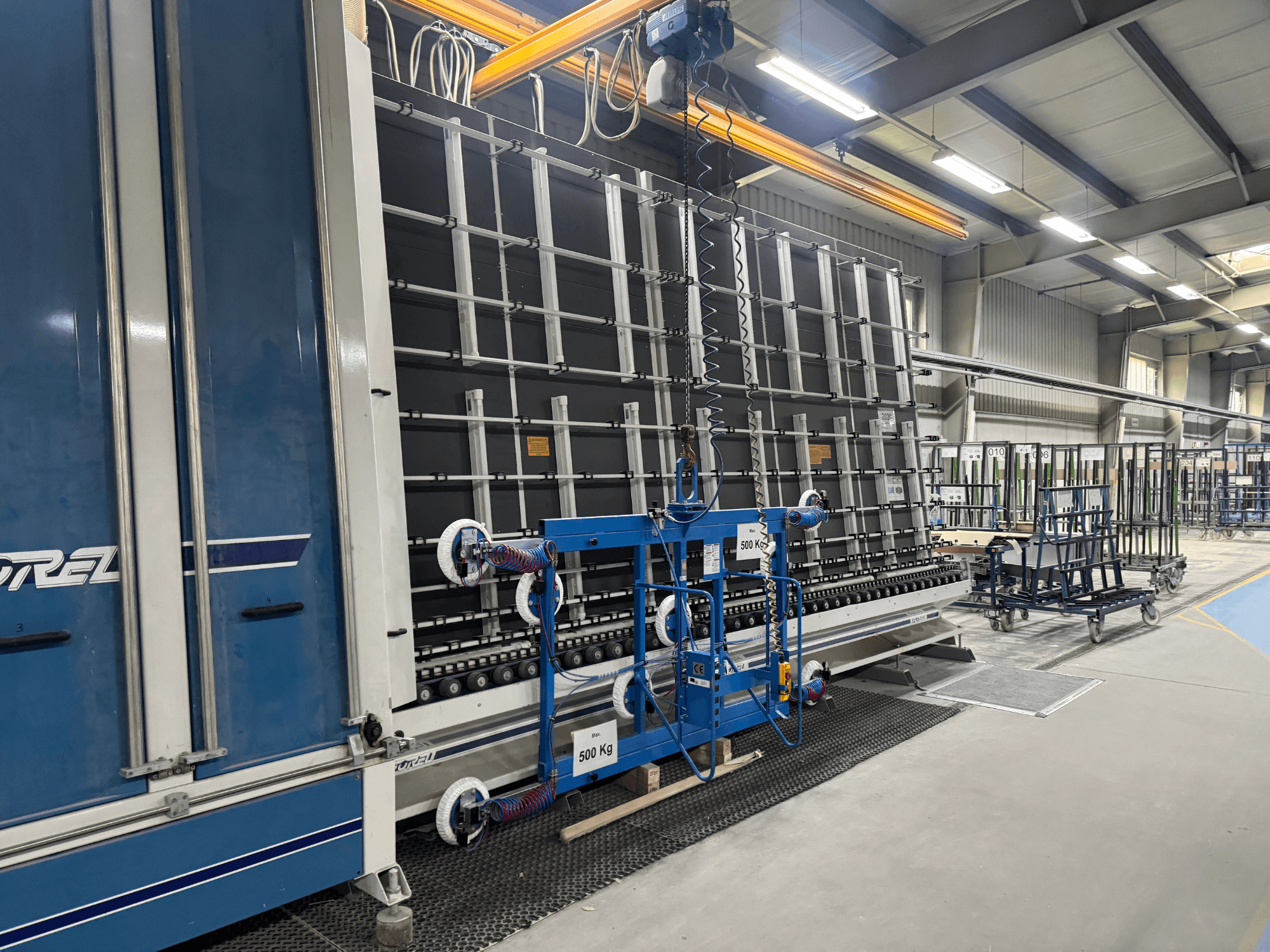 Equipamento industrial da Drel, com uma estrutura de grandes dimensões e um mecanismo de elevação, apresentado de lado numa fábrica.