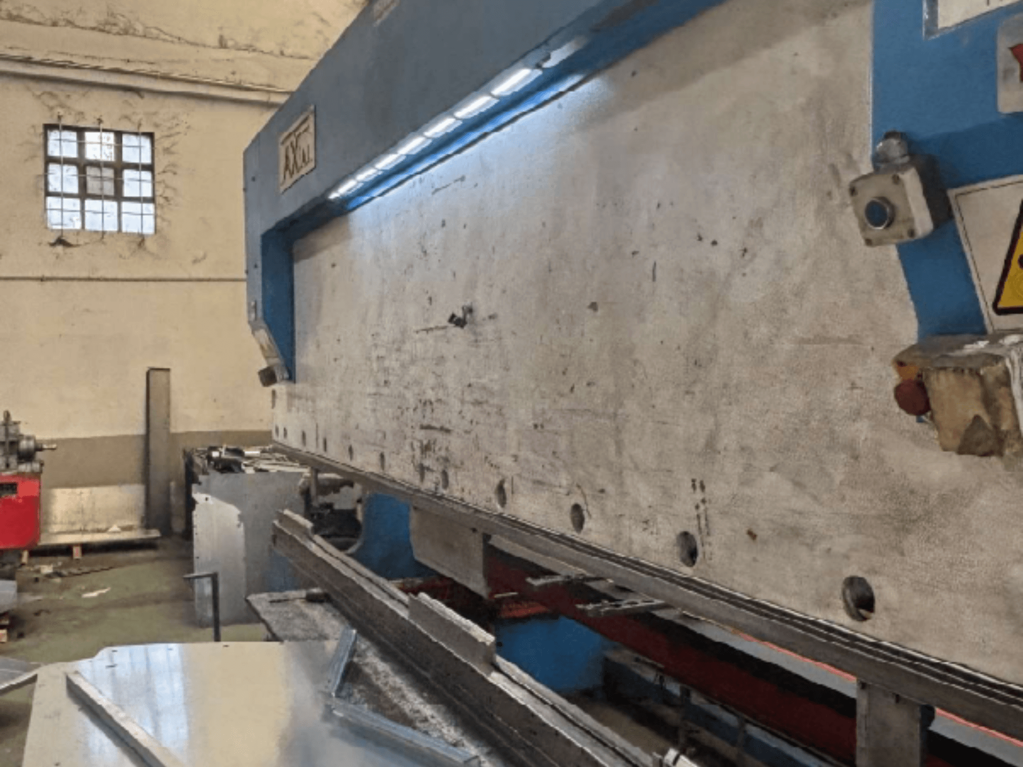 Sistema de manuseamento de paletes Axial PHS-W-124 numa oficina, vista lateral mostrando a superfície de trabalho e os detalhes do painel de controlo.