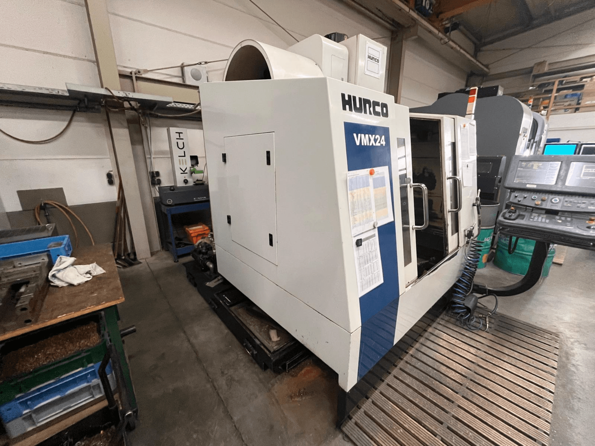 Máquina CNC Hurco VMX24 numa oficina, vista frontal; possui um painel de controlo e uma porta de acesso aberta.