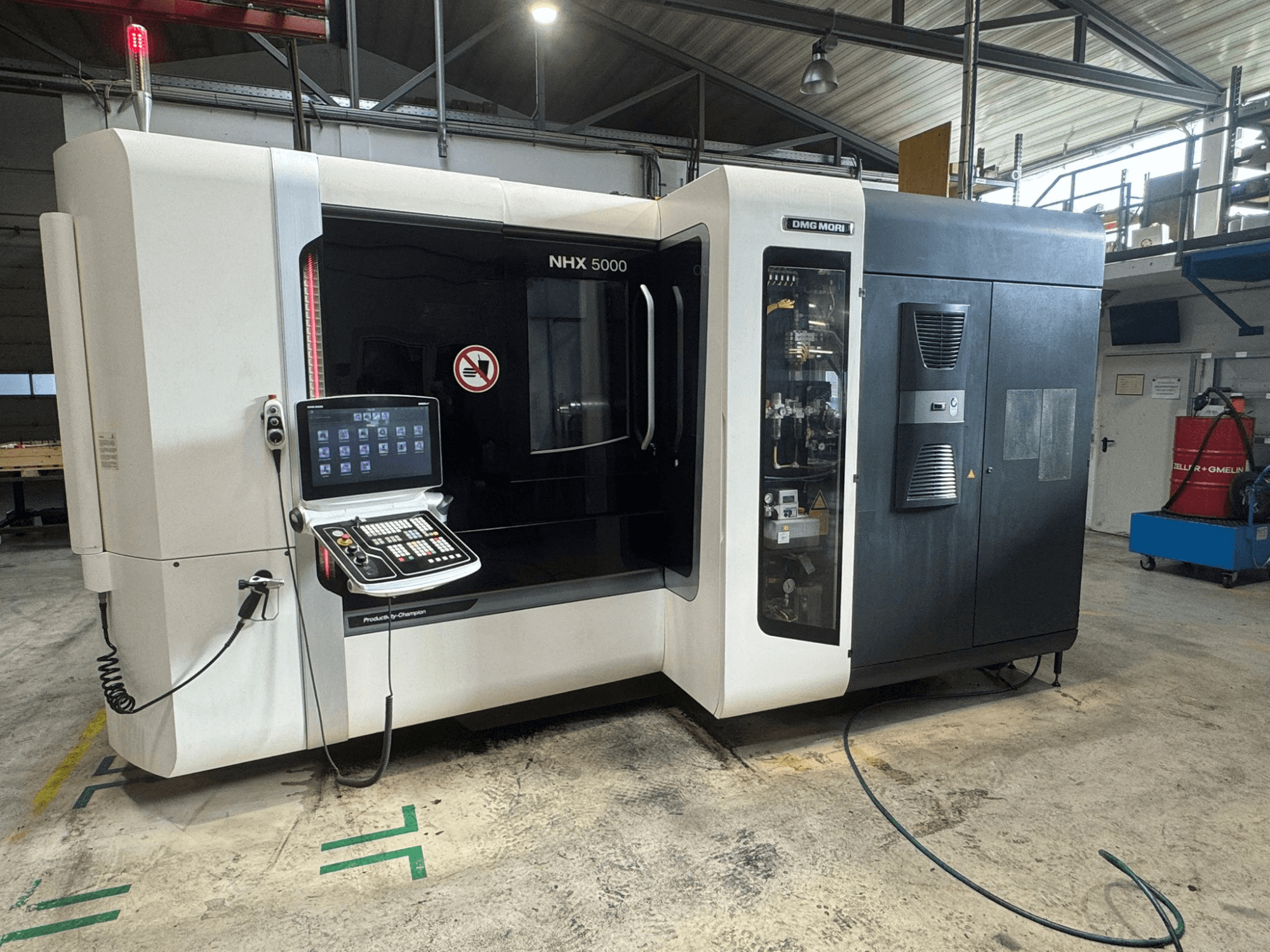 Centro de maquinação horizontal DMG MORI NHX 5000, vista frontal com painel de controlo visível e indicadores de segurança.