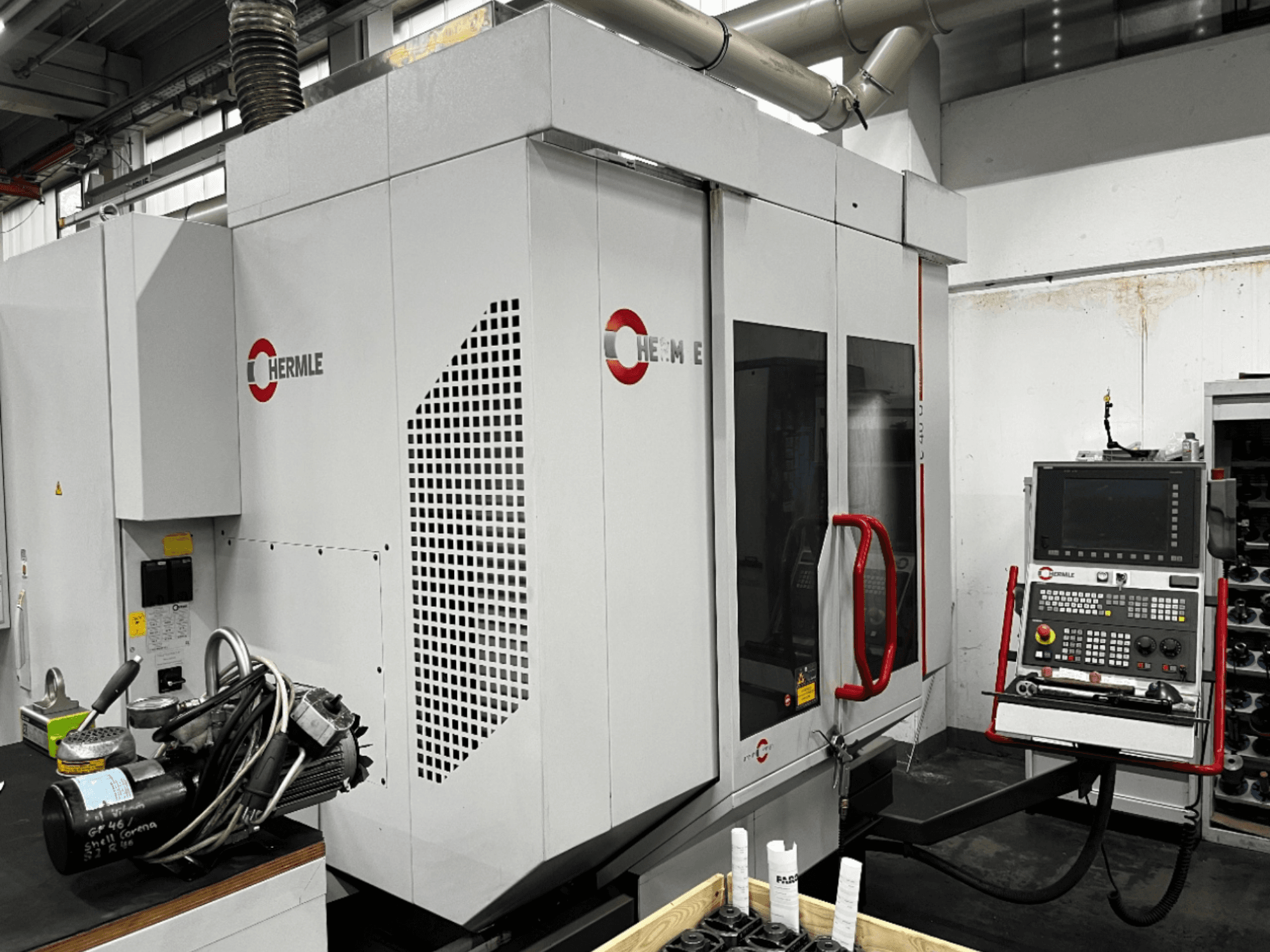 Centro de maquinação universal HERMLE C40U numa oficina, vista frontal, mostrando o painel de controlo e o desenho detalhado da máquina.