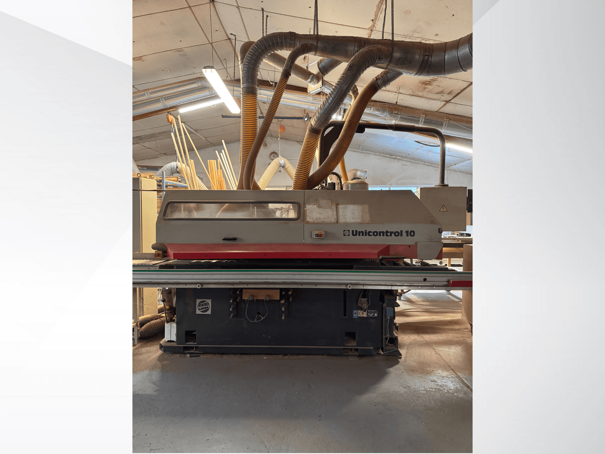 Vista frontal de uma máquina para trabalhar madeira Unicontrol 10, com tubos de extração de poeiras e comandos operacionais.