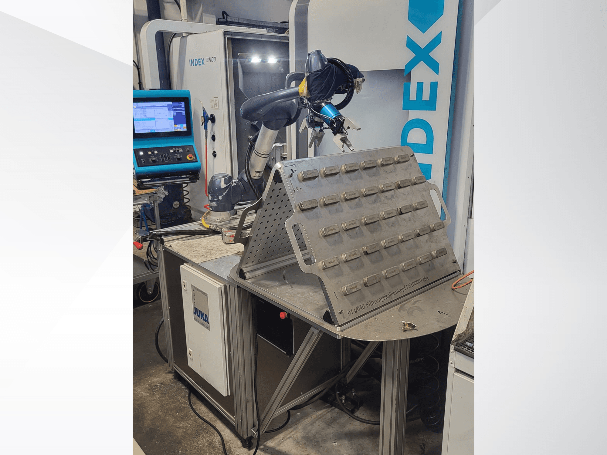 Robô colaborativo DOOSAN M1013 em vista frontal, posicionado perto de uma mesa de trabalho com um suporte de ferramentas e um painel de controlo.