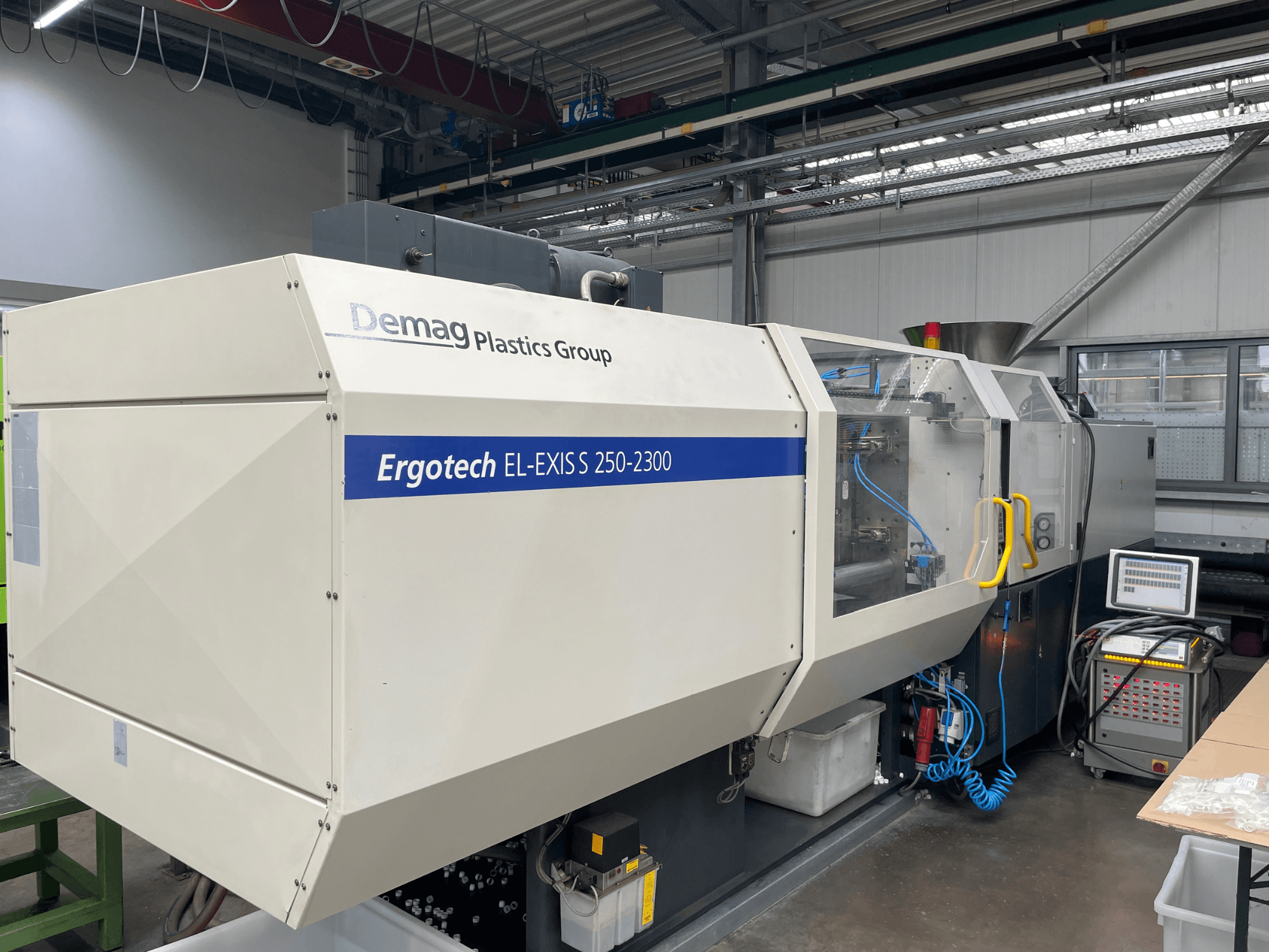 Máquina de moldagem por injeção Demag Ergotech EL-EXIS S 250-2300, vista lateral, mostrando o painel de controlo e o sistema de alimentação.