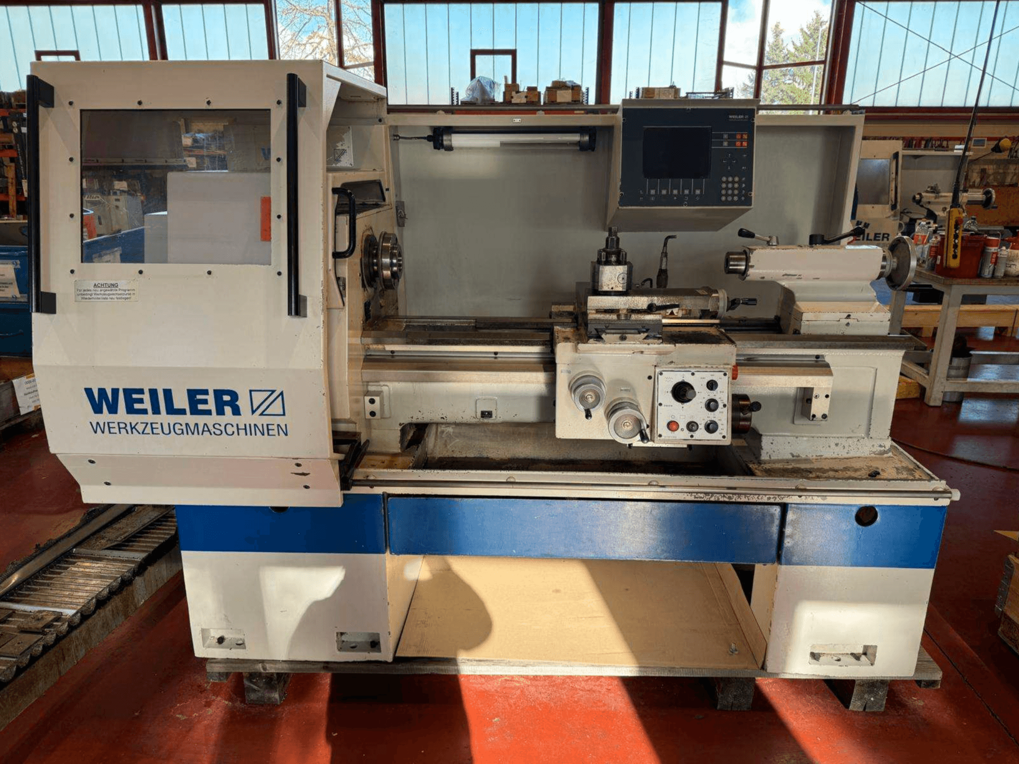Torneiro horizontal Weiler E35 em vista frontal, com painel de controlo e componentes de torno.