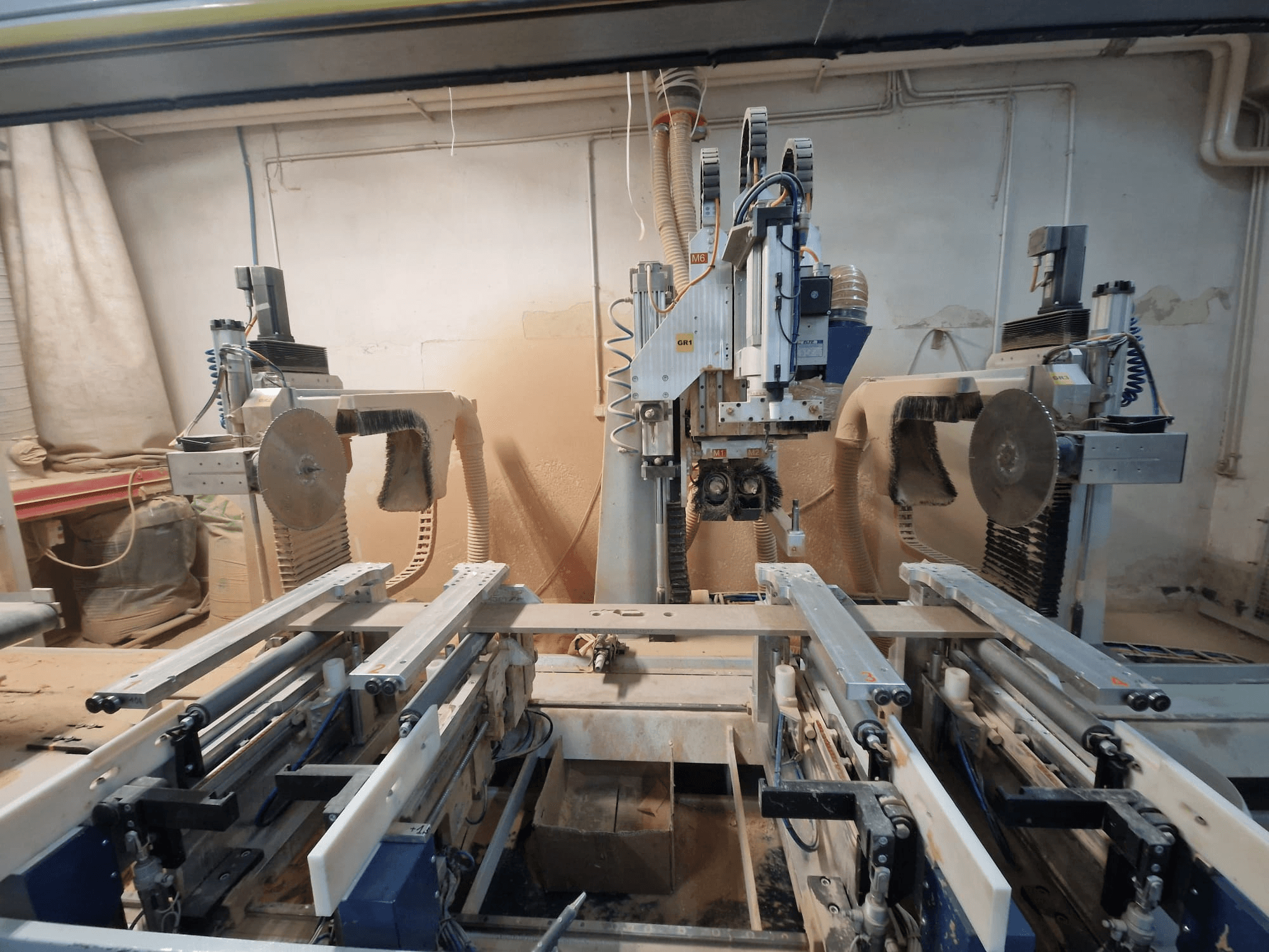 Máquina CNC com duas lâminas de serra e calhas, vista de frente. Sistemas de extração de poeiras visíveis, adequados para o trabalho da madeira.