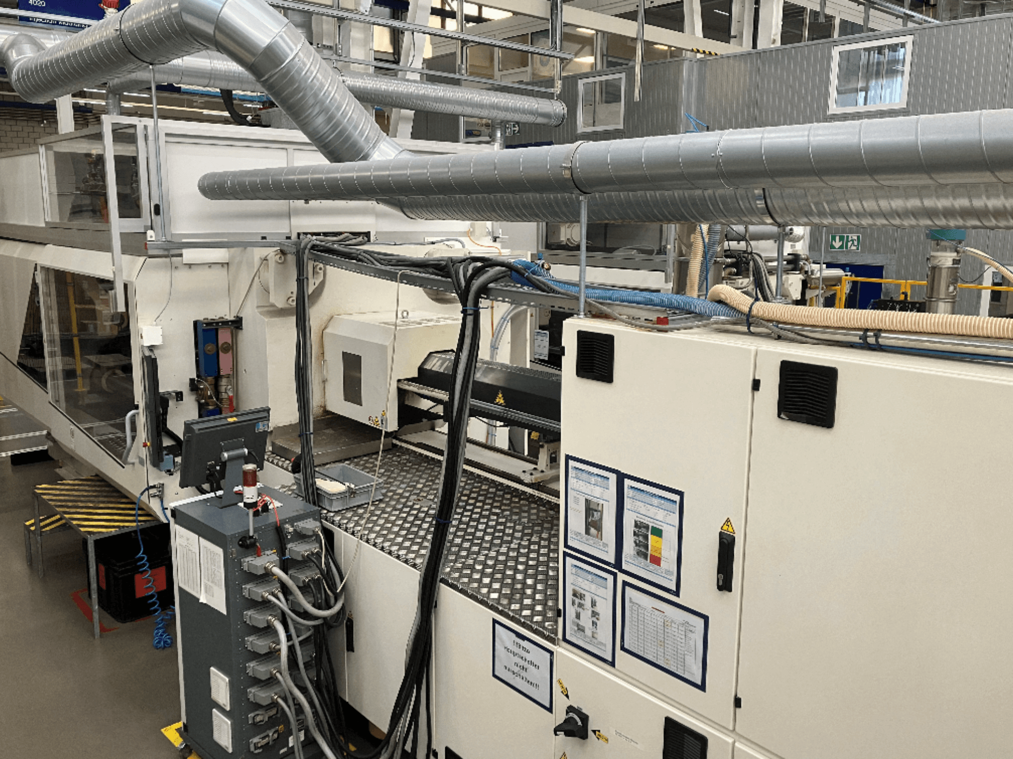 Máquinas industriais com tubagem extensa, painel de controlo e manuais de operação, vistos de uma perspetiva de cima para baixo.