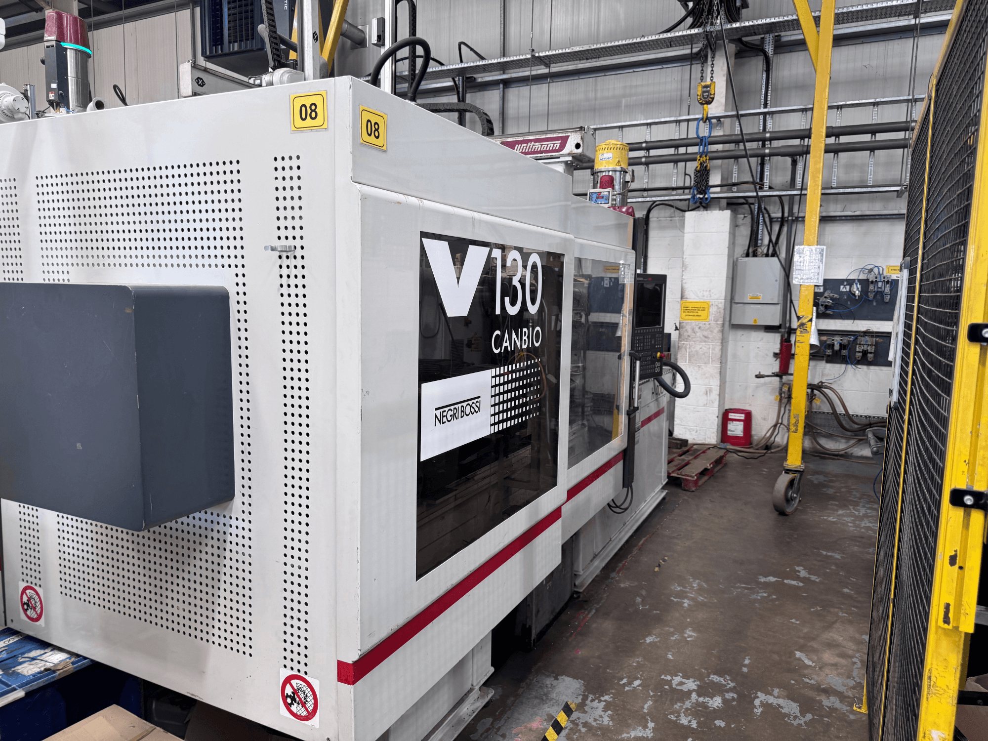 Máquina de moldagem por injeção hidráulica Negri Bossi 1300H-400, vista lateral, com painel de controlo e sinalização de segurança.
