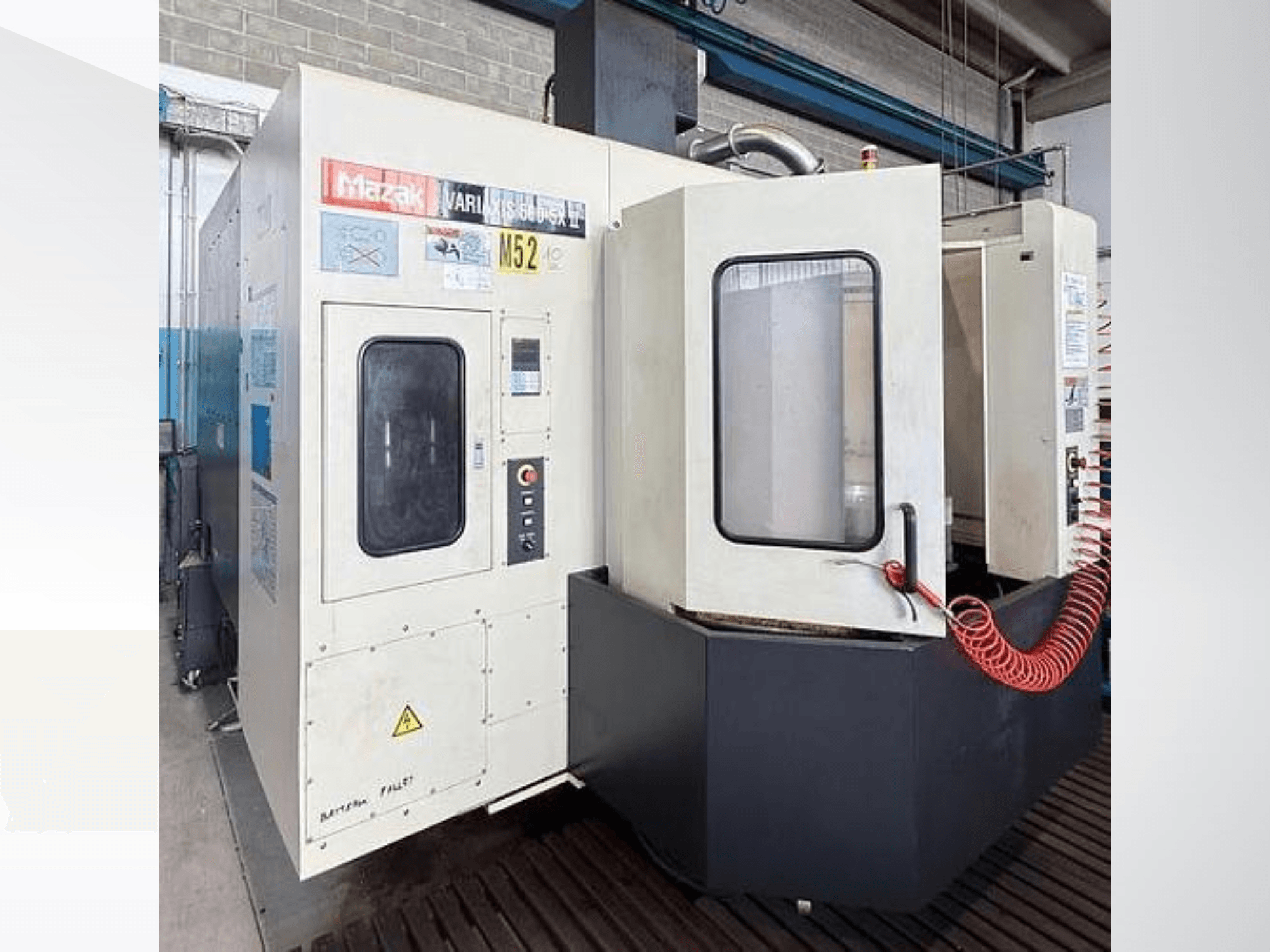 Centro de maquinagem vertical Mazak VARIAXIS500-5XII, vista frontal; com um painel de controlo e uma janela de visualização.