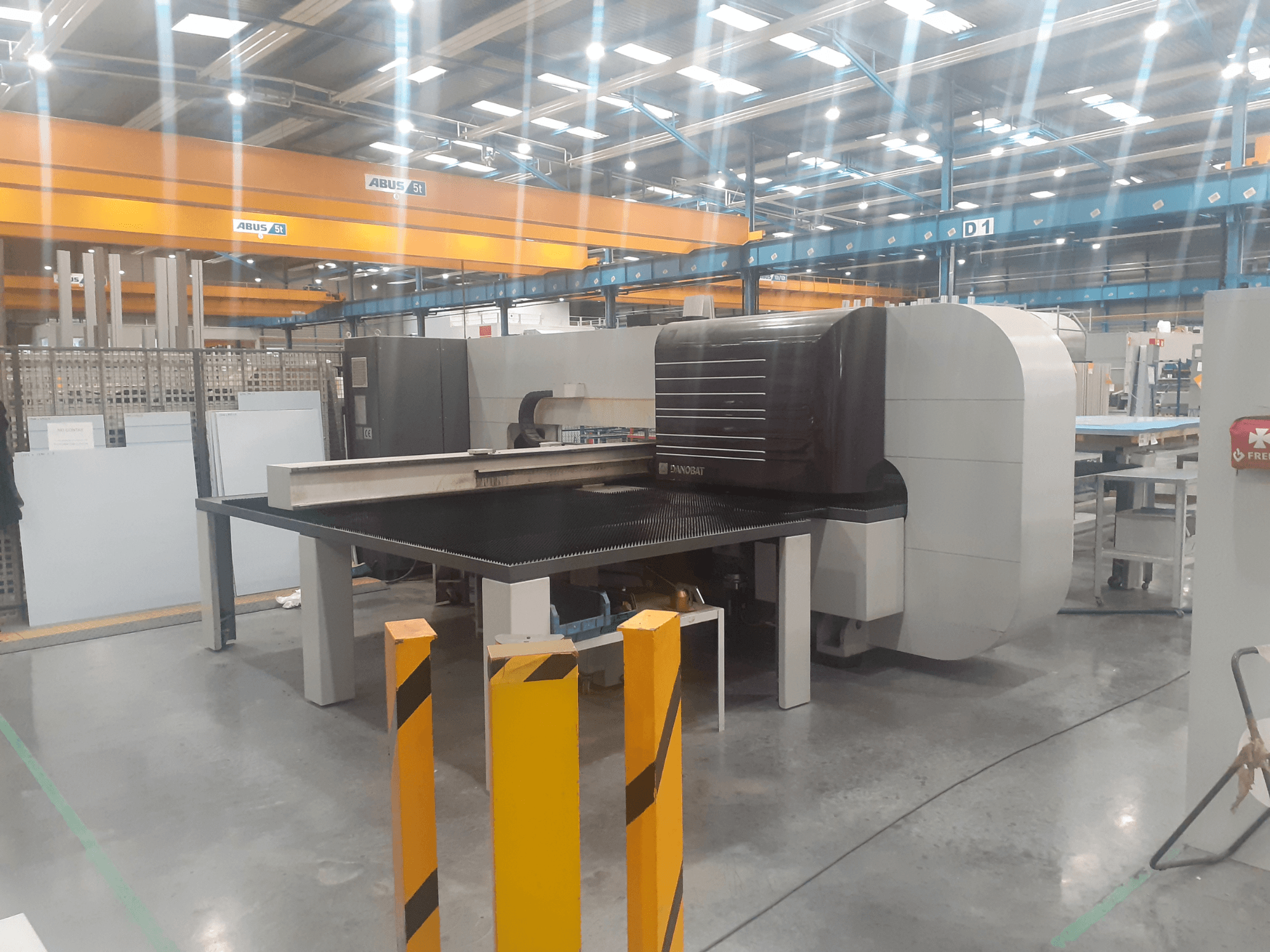 Rectificadora cilíndrica DANOBAT CHROMA 30 na oficina, vista lateral mostrando uma grande mesa e barreiras de segurança em primeiro plano.