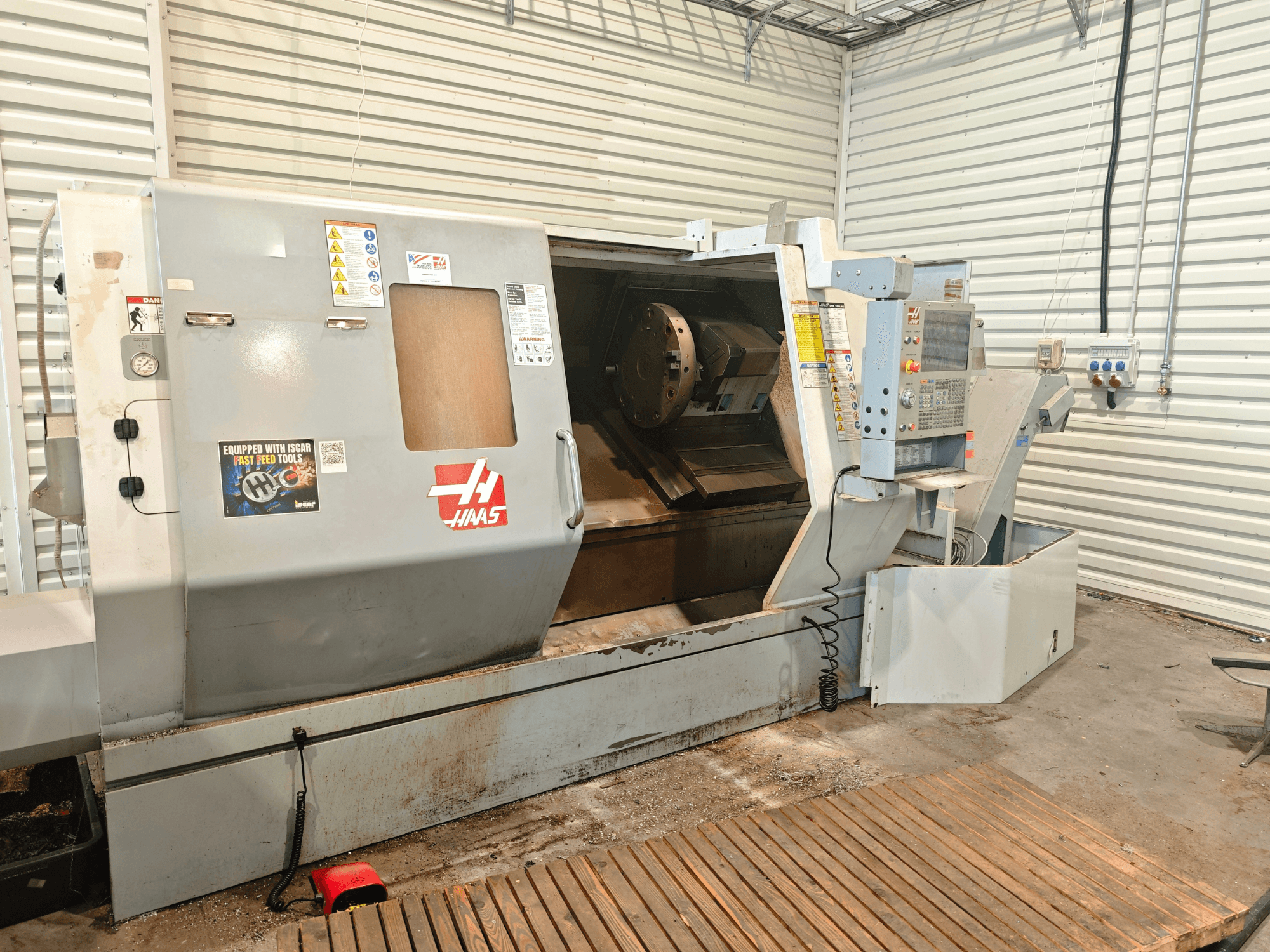 Torno horizontal Haas SL-40HE, vista frontal, mostrando o painel de controlo, a área de trabalho e as etiquetas de segurança.