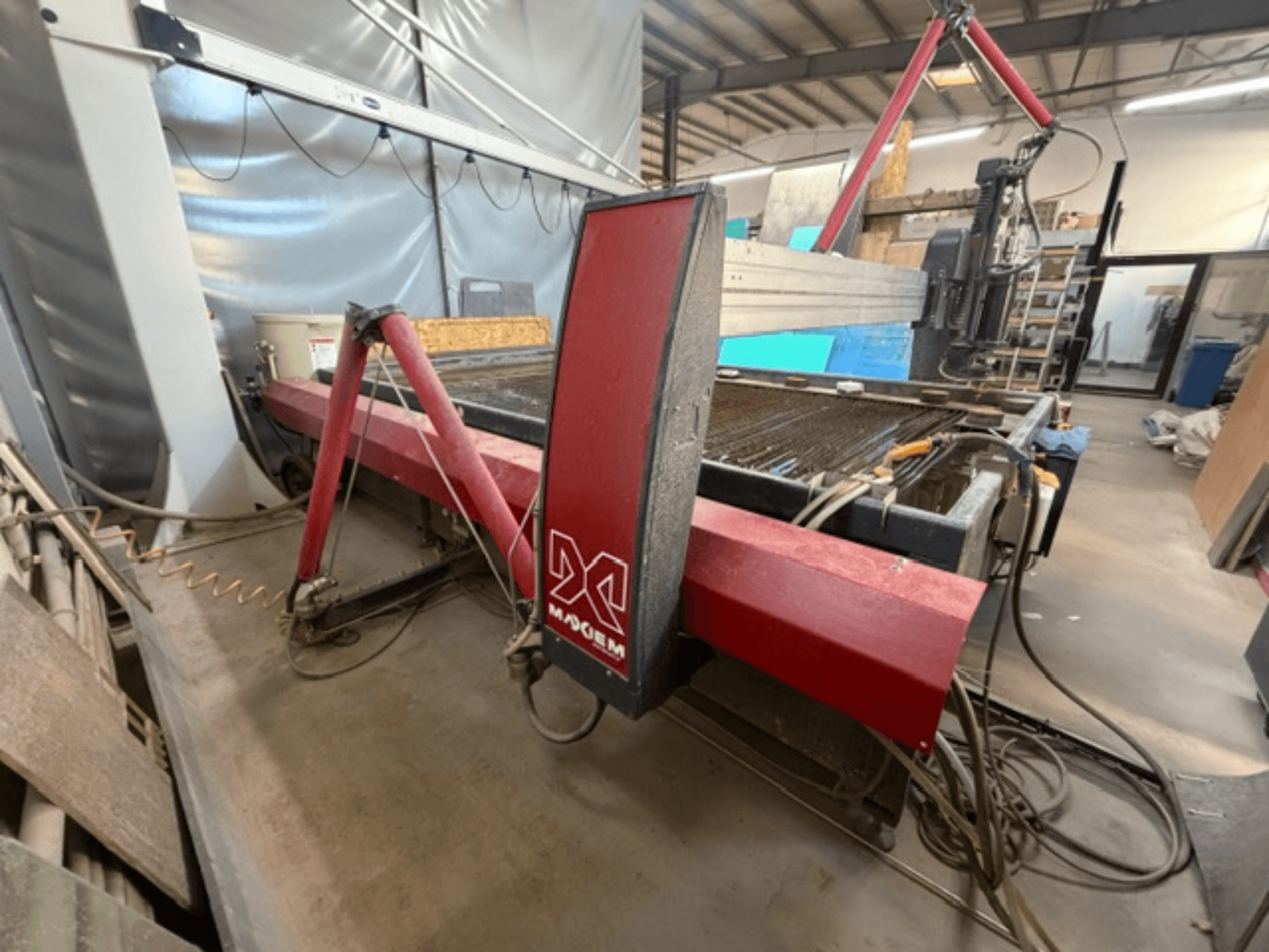 Máquina de corte por jato de água vermelha da marca X, vista de lado, mostrando os componentes mecânicos e os detalhes da tubagem.