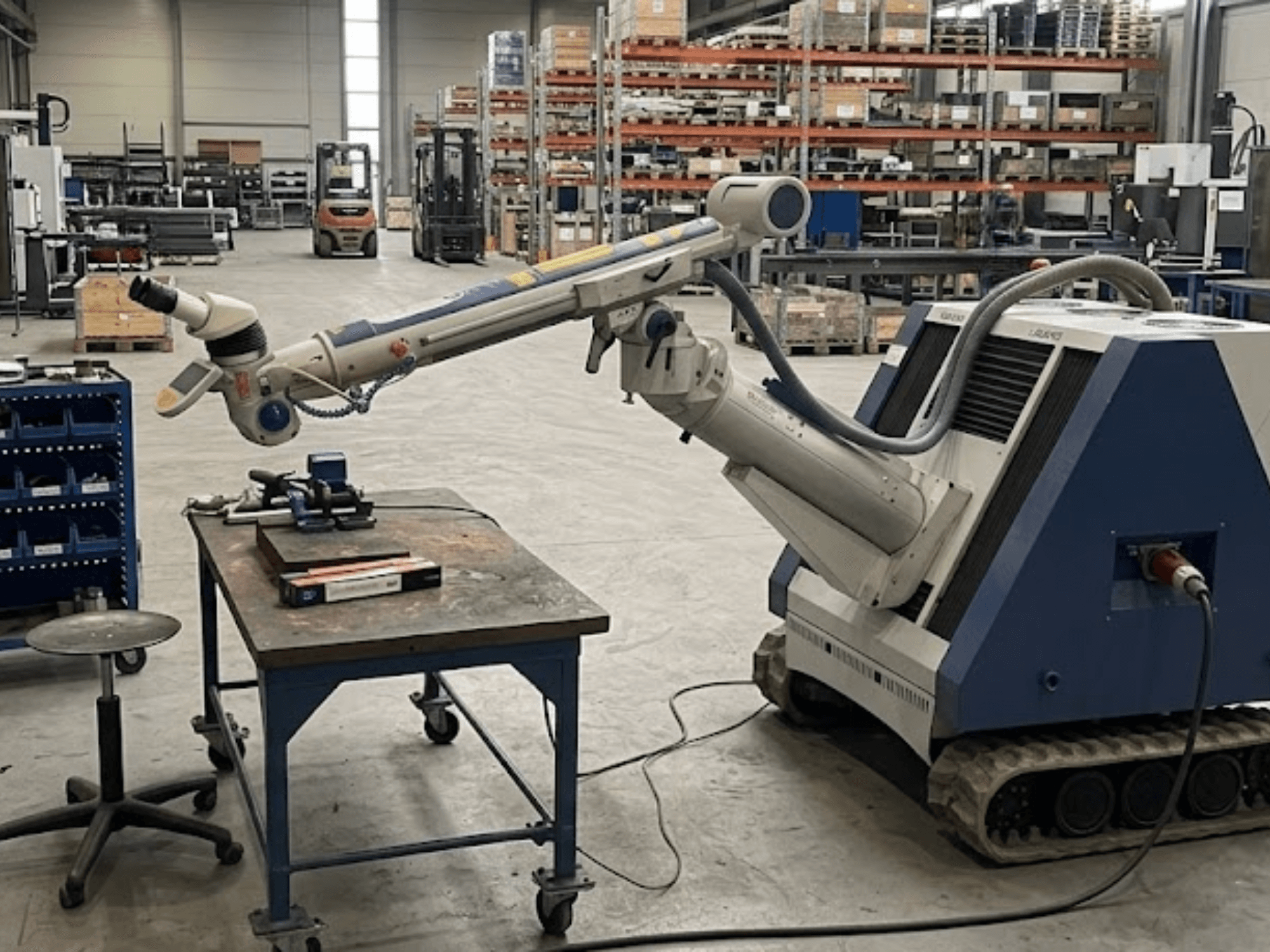 Máquina-ferramenta ALPHA LASER ALFlak300 M numa oficina com braço robótico; vista frontal que mostra a configuração de precisão na mesa de trabalho.