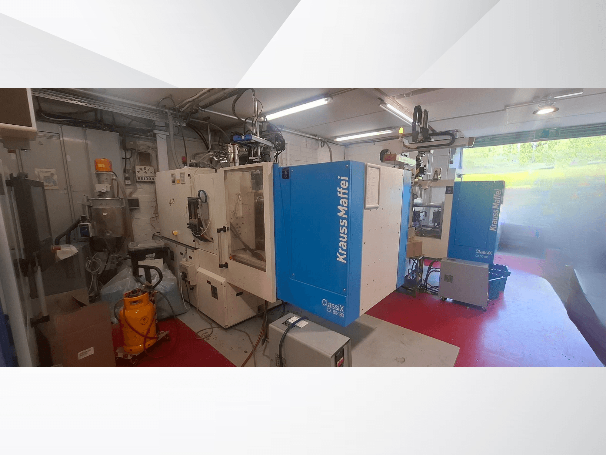 Máquina de moldagem por injeção hidráulica Krauss Maffei CX 80-180, vista frontal, num ambiente industrial, rodeada por equipamento.