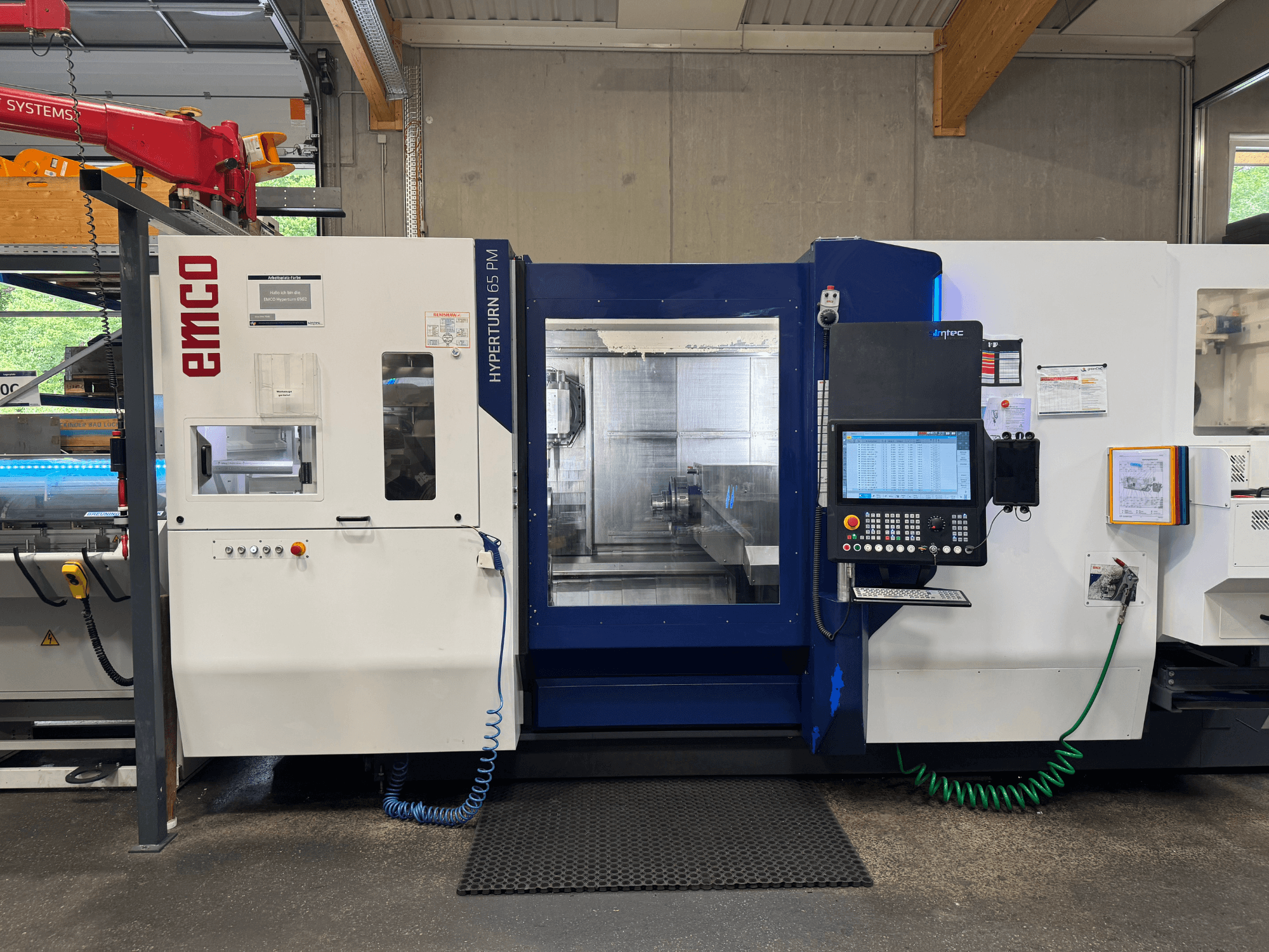 Máquina EMCO Hyperturn 65 PM, vista frontal, mostrando o painel de controlo, a área do fuso e as caraterísticas operacionais.