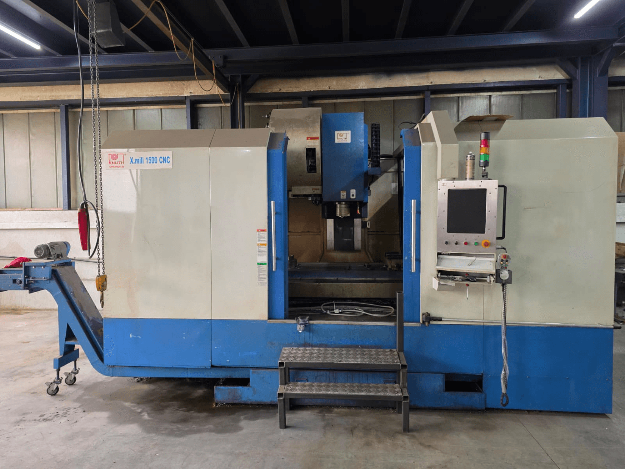 Centro de maquinagem vertical CNC KNUTH X-MILL 1500, vista lateral, com painel de controlo, degraus e transportador de saída.
