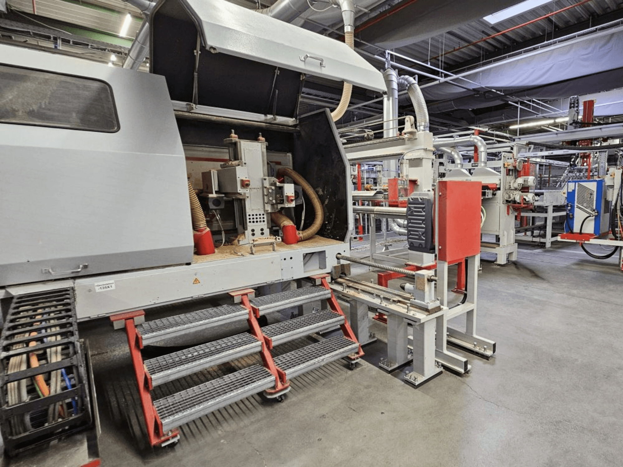 Vista frontal da linha de produção de madeira BURKLE Optima 1428/50, com degraus e componentes de máquinas visíveis.
