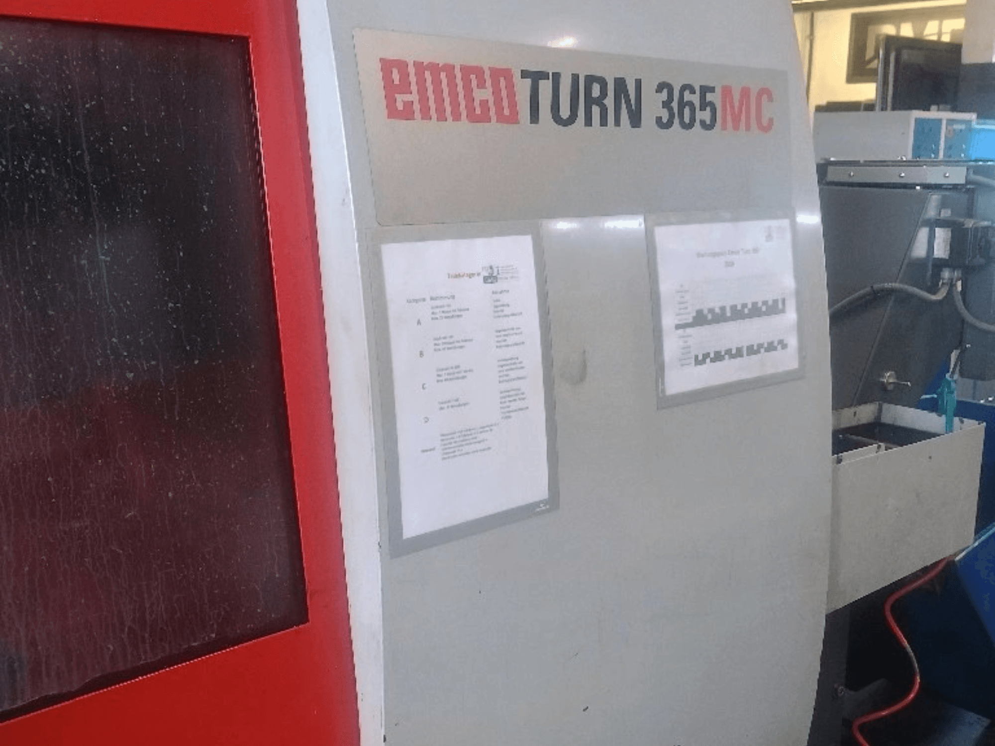 Torno horizontal EMCO EmcoTurn 365 MC, vista lateral com painel de controlo, manuais e depósito azul de líquido de arrefecimento visíveis.