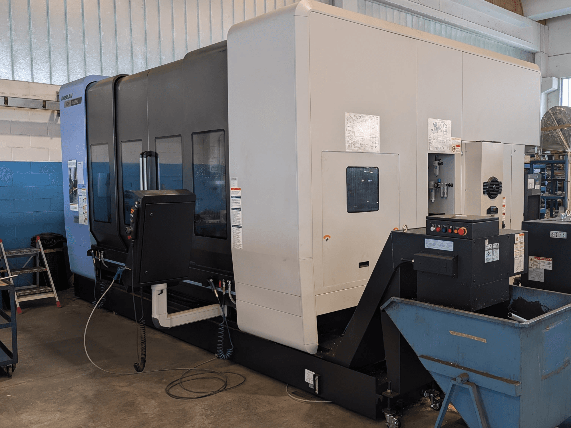 Centro de maquinagem vertical DOOSAN VCF850LSR-II visto de lado, mostrando o painel de controlo, o sistema de refrigeração e a sua construção robusta.