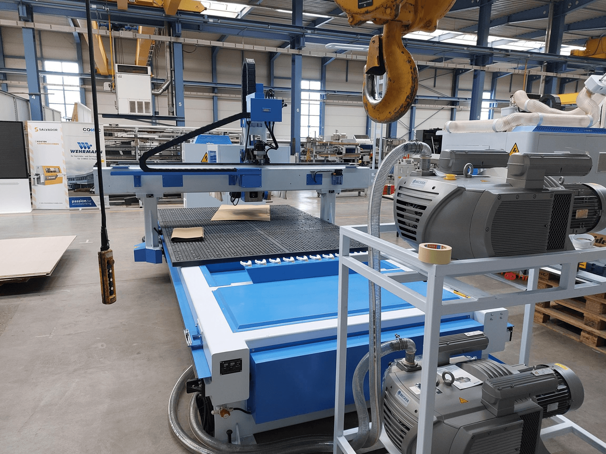 Centro de usinagem de madeira CNC QUICK CNC UA 481, vista frontal que mostra o painel de controlo, os motores e a superfície de trabalho com uma peça de madeira.