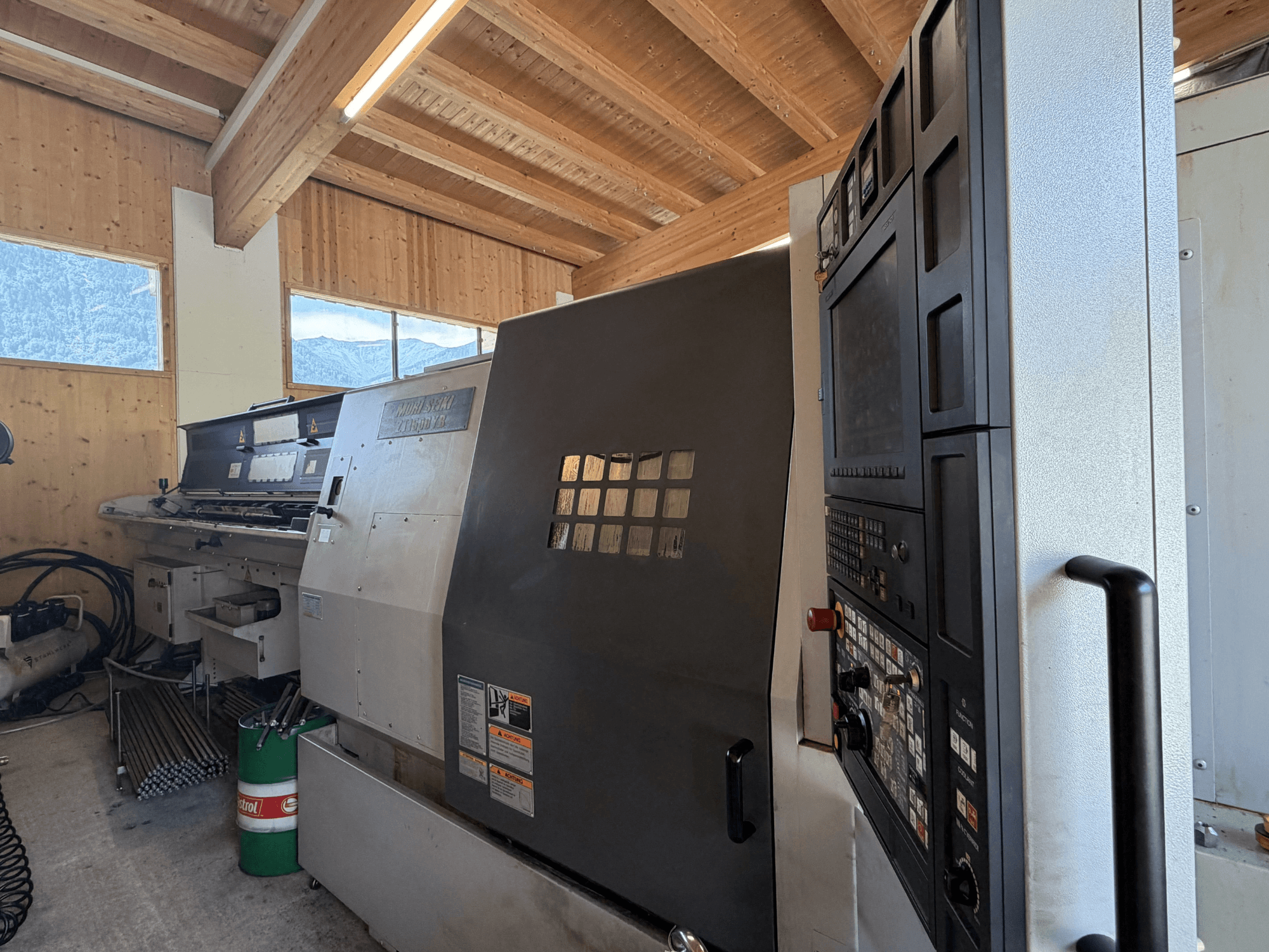Centro de torneamento e fresagem MORI SEIKI ZT1500YB numa oficina, vista lateral que mostra o painel de controlo e as características da máquina.