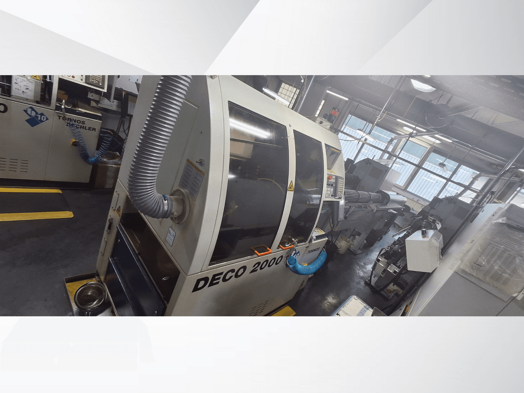 Máquina CNC DECO 2000 na oficina, vista frontal, com mangueira de ventilação e painel de controlo, concebida para maquinação de precisão.