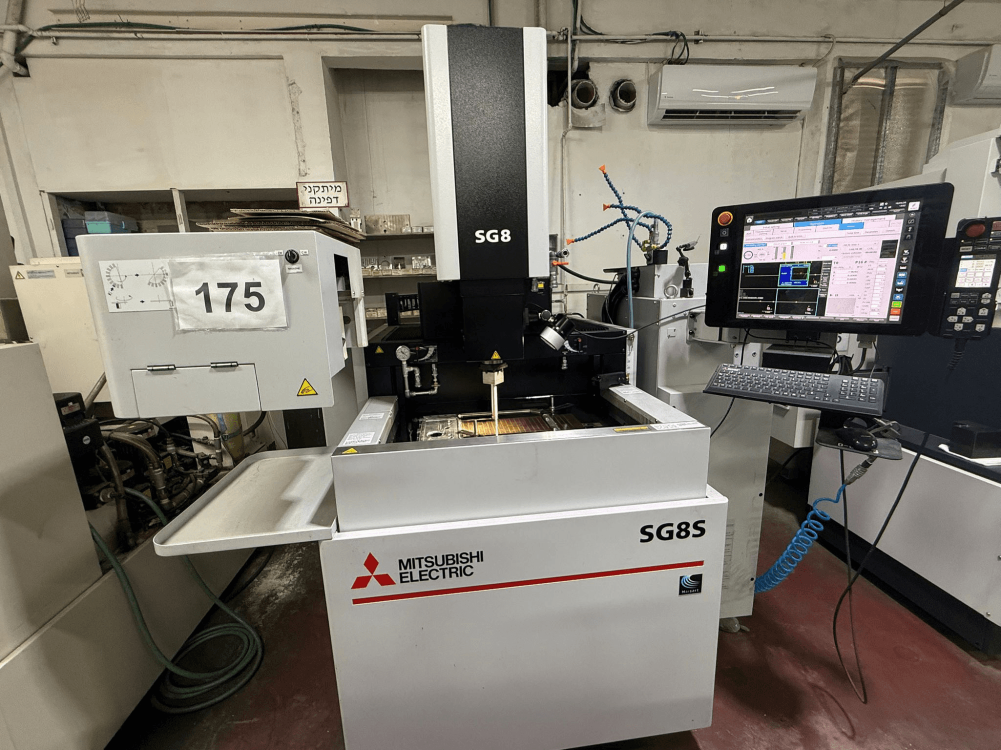 Máquina EDM para confeção de matrizes SG8S da Mitsubishi, vista frontal com monitor e painel de controlo visíveis; a área de trabalho mostra a configuração da ferramenta.