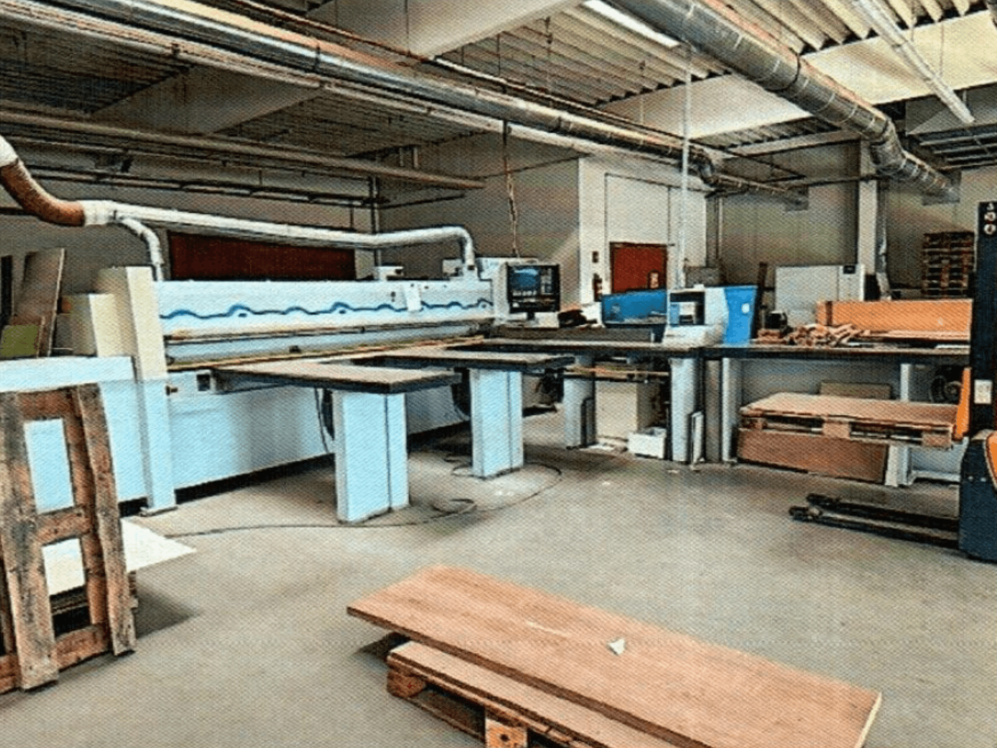 Serra de painel HOMAG HPL 11/38/22 numa oficina, com uma grande mesa de corte e uma consola de exposição, vista de frente.