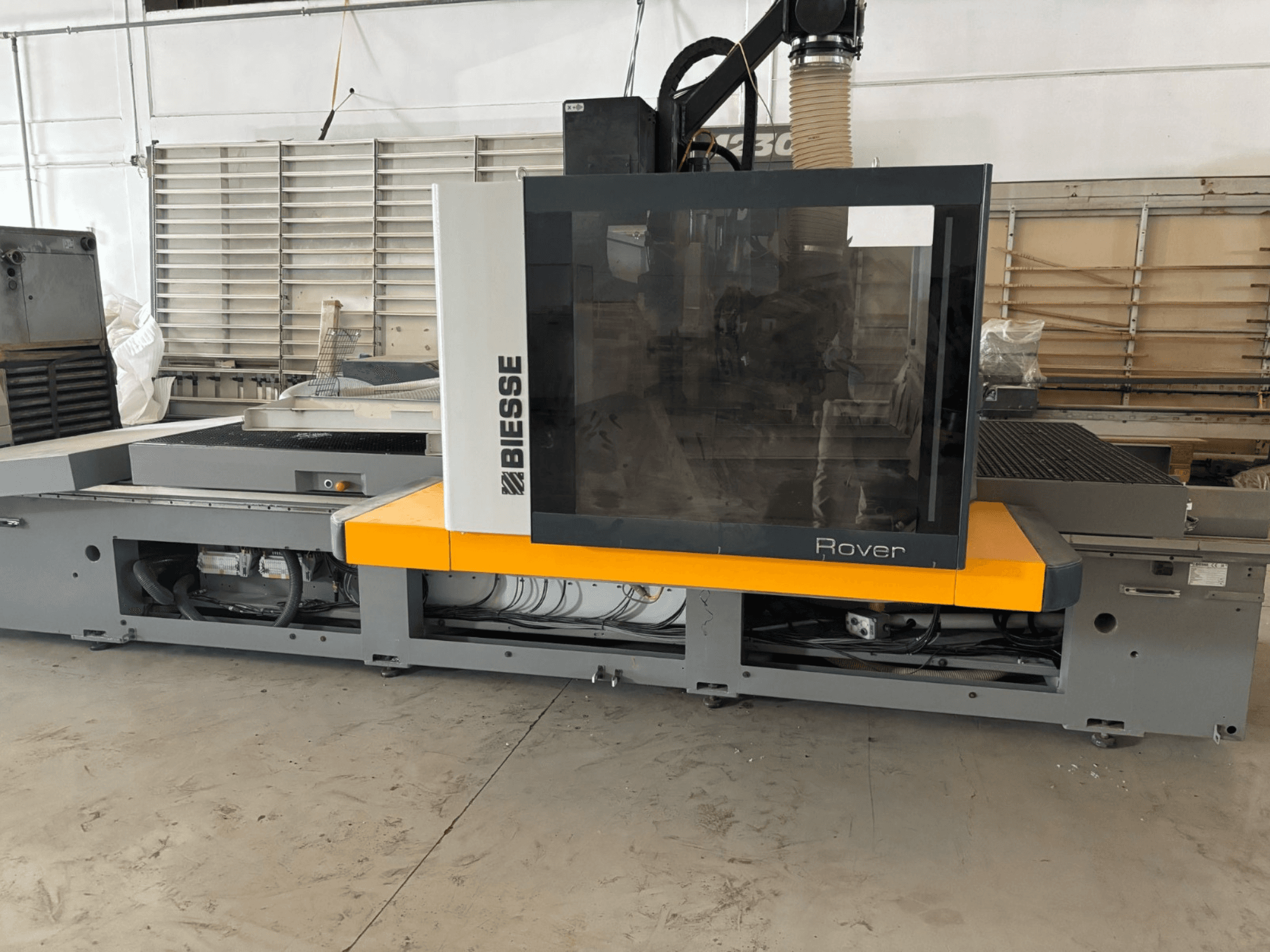 O centro de maquinação CNC Biesse Rover, vista frontal, apresenta um grande painel de controlo, detalhes em amarelo e componentes mecânicos expostos.