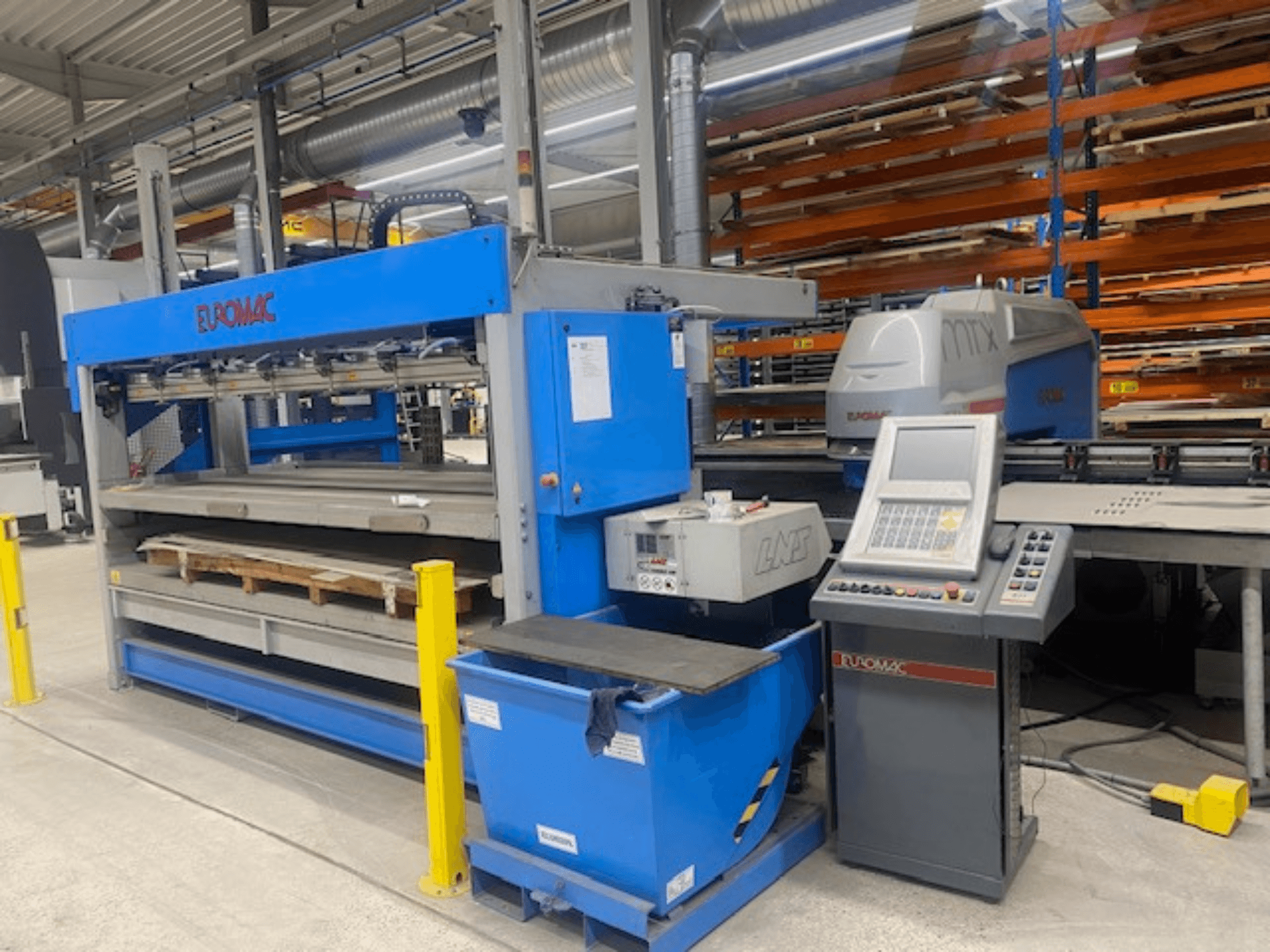 Máquina de perfuração CNC Euromac MTX FLEX 12, vista frontal com o painel de controlo, paletes e dispositivos de segurança visíveis.
