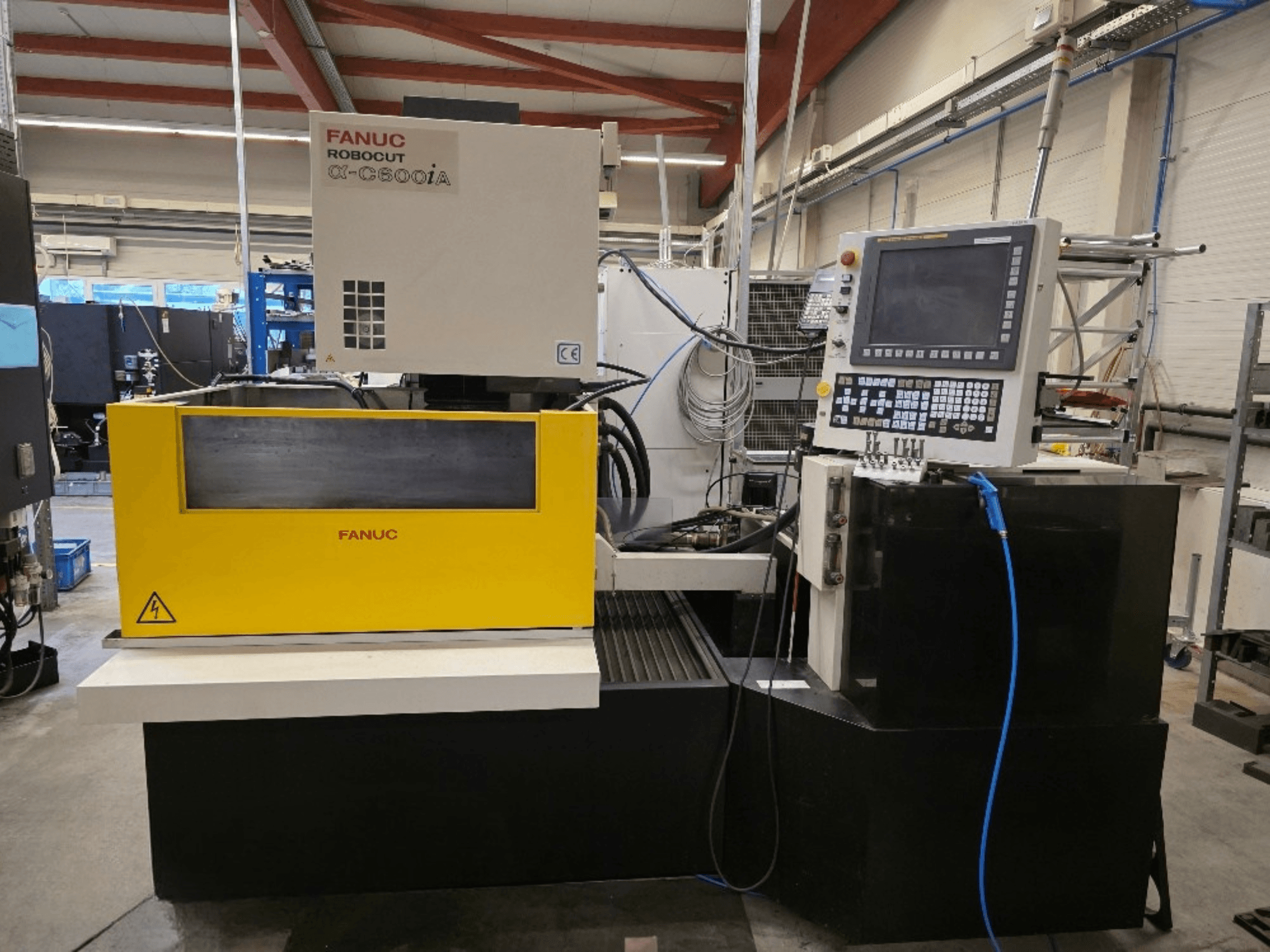 Máquina de corte a fio FANUC Robocut α-C600iA, vista frontal, com um painel de controlo amarelo e um visor digital.