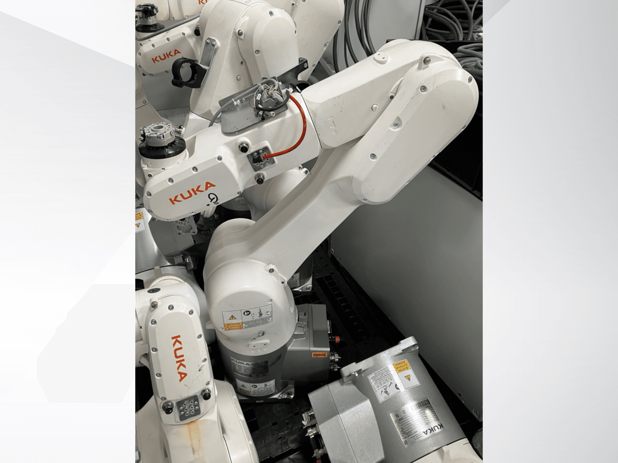 Braço do robô KUKA KR 6 R900 CR, vista lateral; possui motores e conectores visíveis, avisos de segurança rotulados e braços mecânicos.