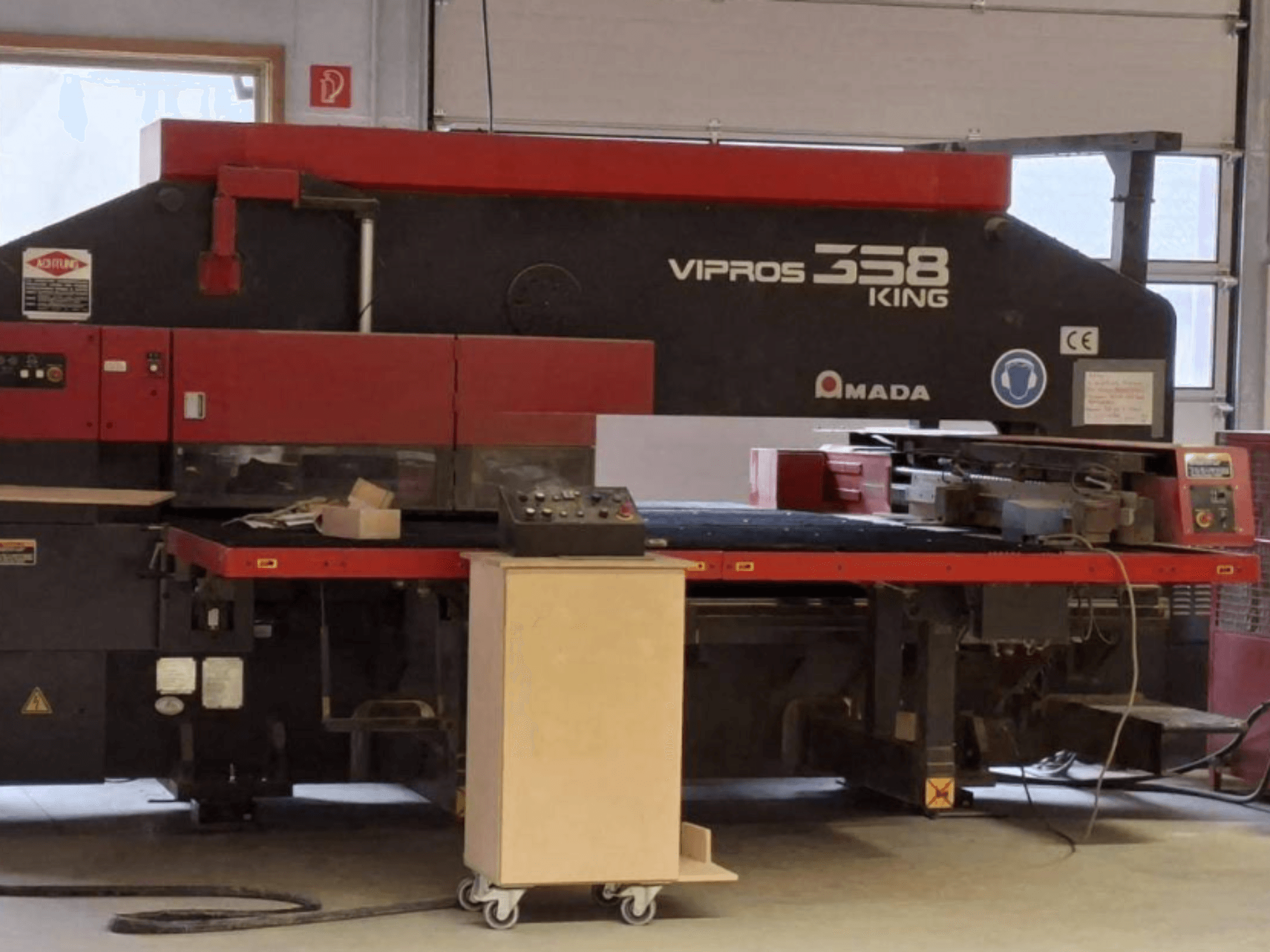 Prensa de perfuração CNC AMADA VIPROS 358 KING vista de lado, com destaque para o painel de controlo e a área de arrumação de ferramentas.