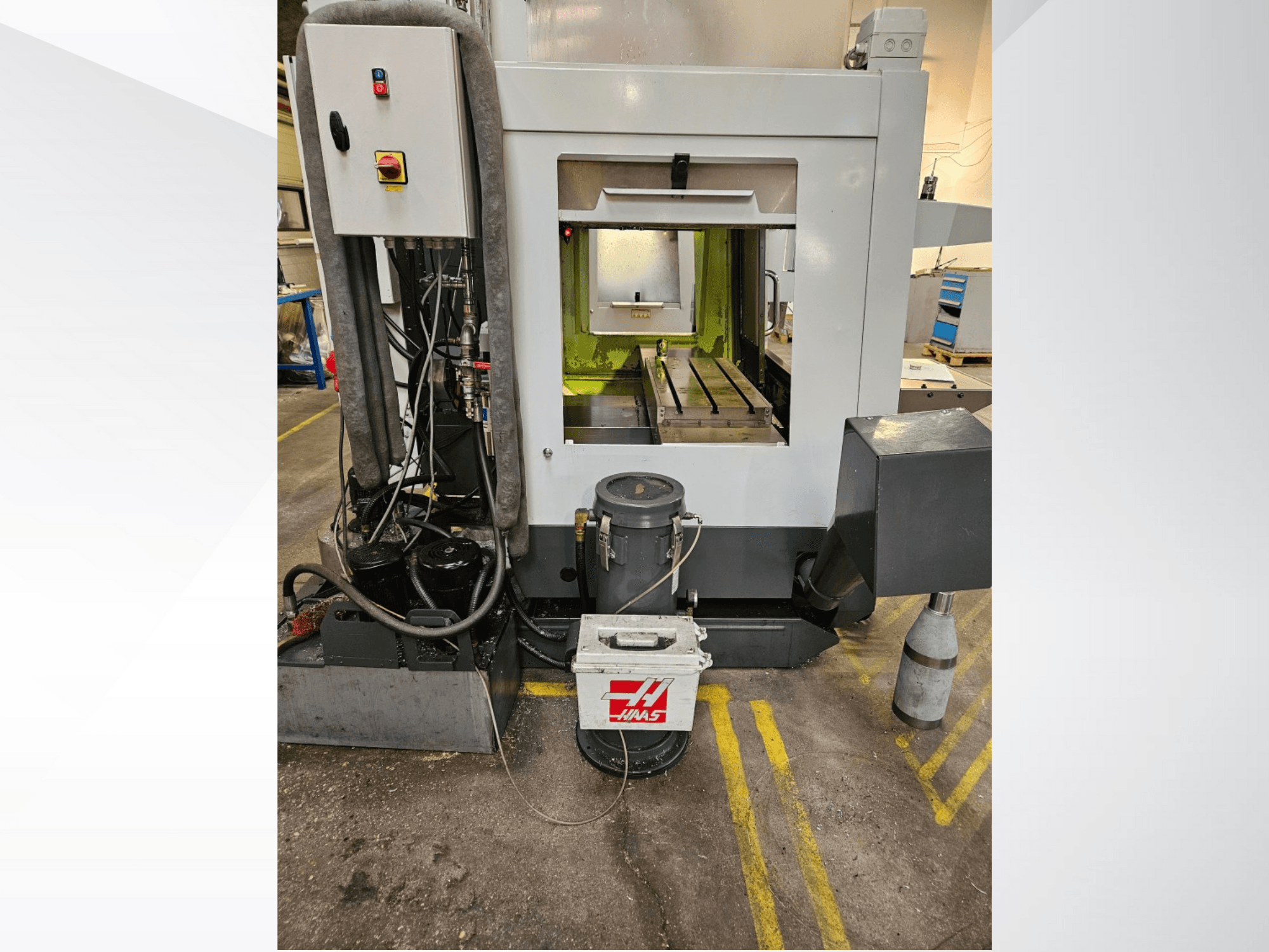 Vista frontal da máquina CNC Haas mostrando o painel de controlo, o tanque de refrigeração e a base maquinada em exposição.