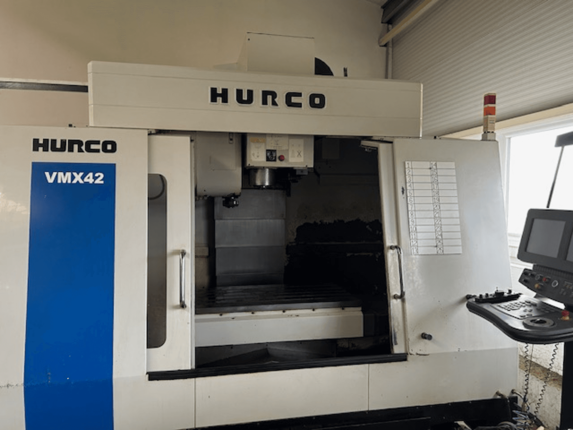 Máquina CNC Hurco VMX42 em vista frontal, mostrando o painel de controlo, o fuso e a área de trabalho; revelando a disposição operacional.