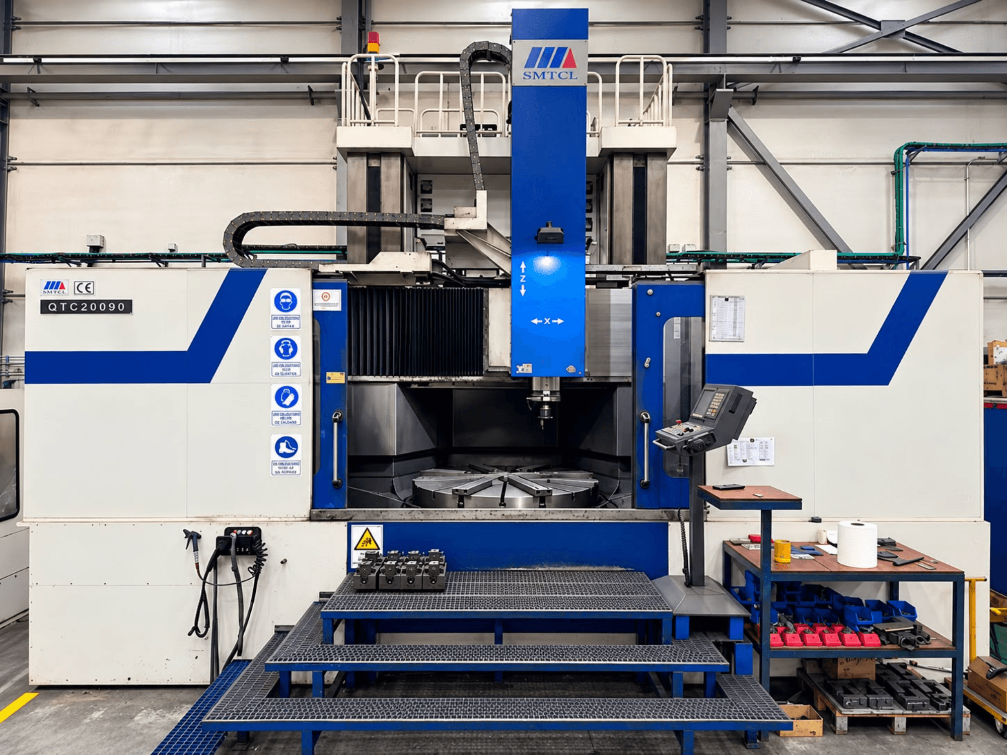 Torno vertical SMTCL QTC 20090 numa oficina, vista frontal, com o painel de controlo e a mesa de trabalho.
