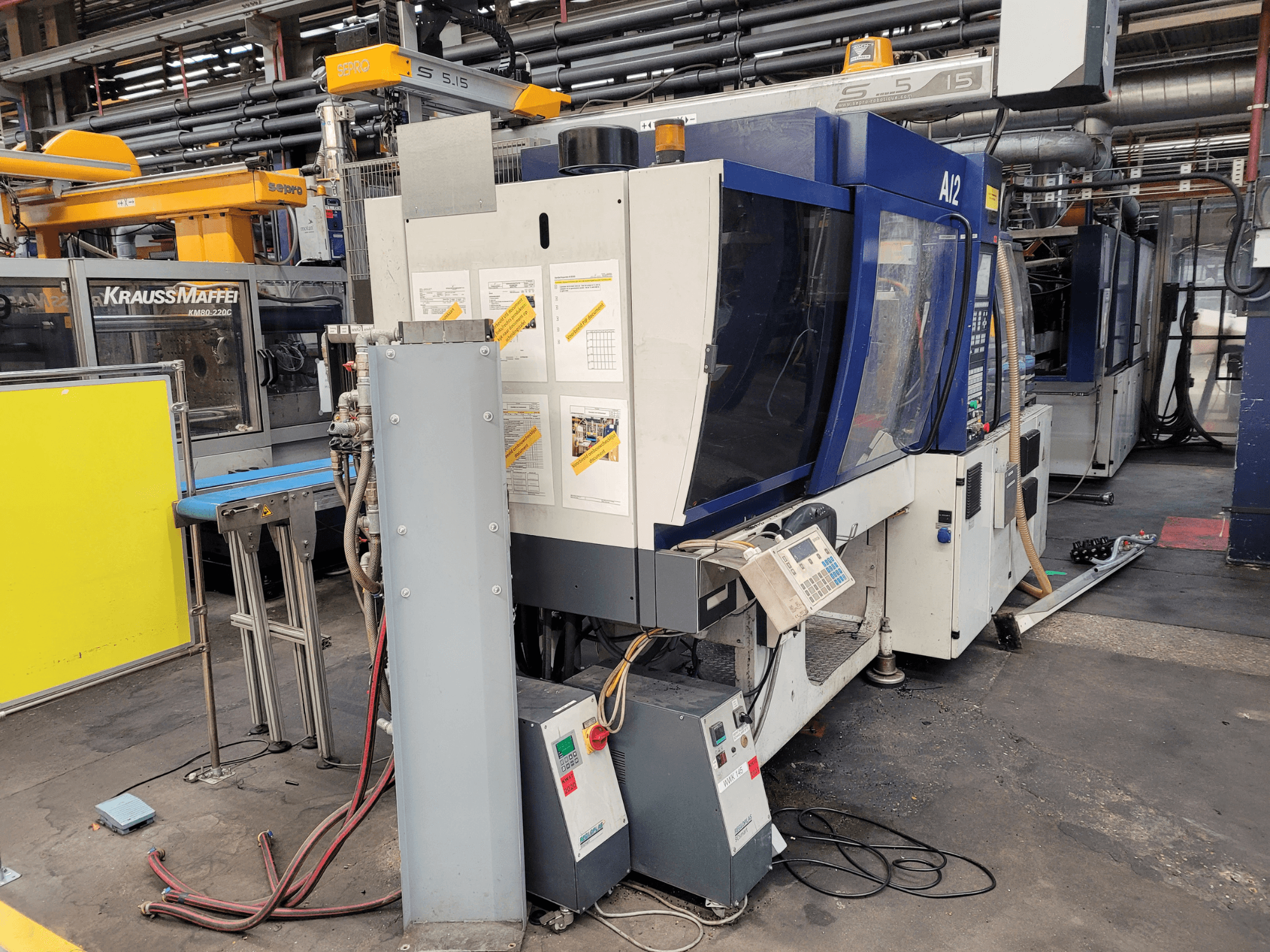 Máquina de moldagem por injeção KraussMaffei modelo KM80-232G, vista frontal, com painel de controlo e componentes operacionais.