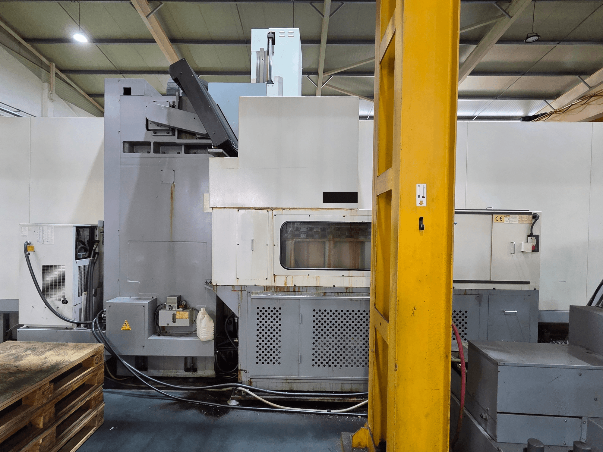 Centro de maquinação vertical HARTFORD HB 3150/S numa oficina, vista lateral mostrando o corpo da máquina e os componentes anexados.