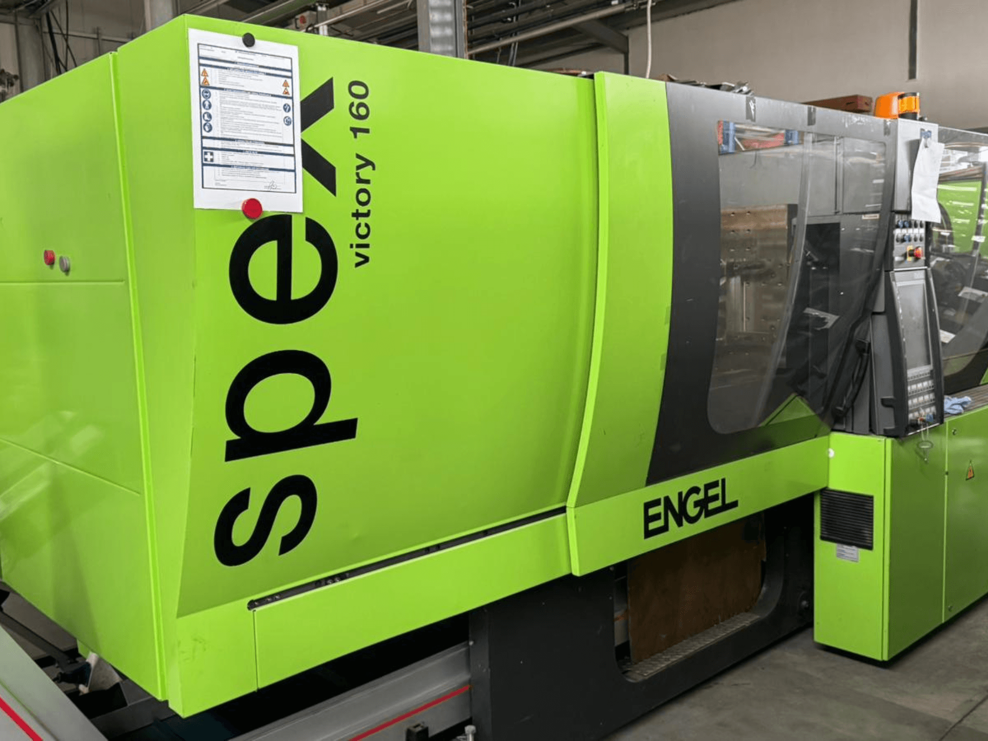 Bright green ENGEL Victory 160 injection molding machine, side view, features control panel and safety signage visible.
