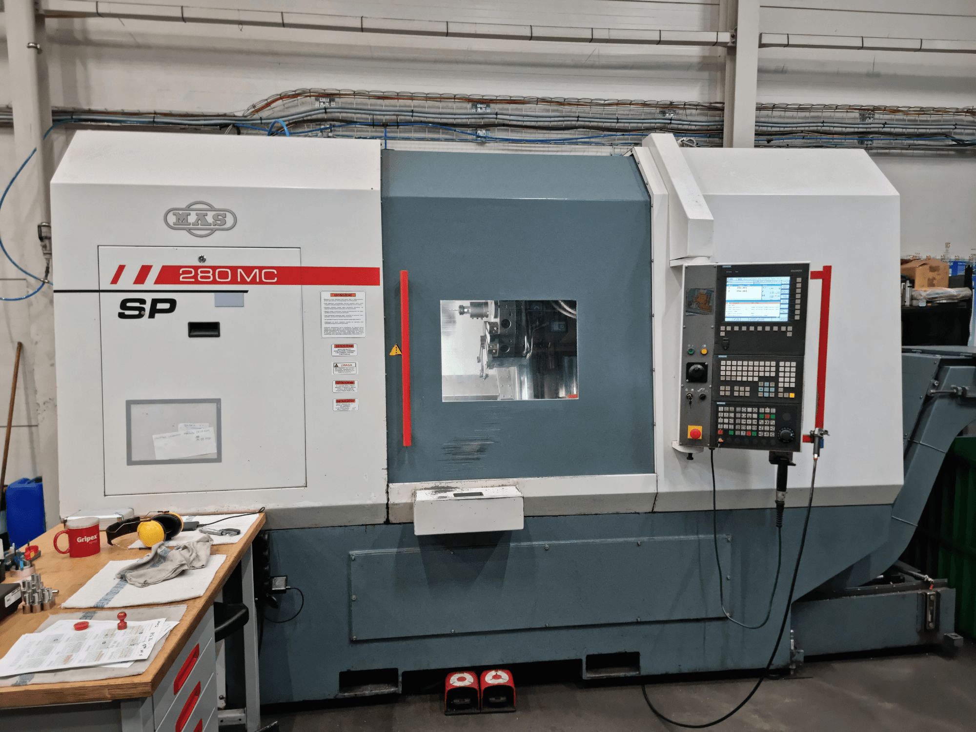 Torno horizontal KOVOSVIT MAS SP 280 MC, visto de frente, com o painel de controlo e a janela de operação.