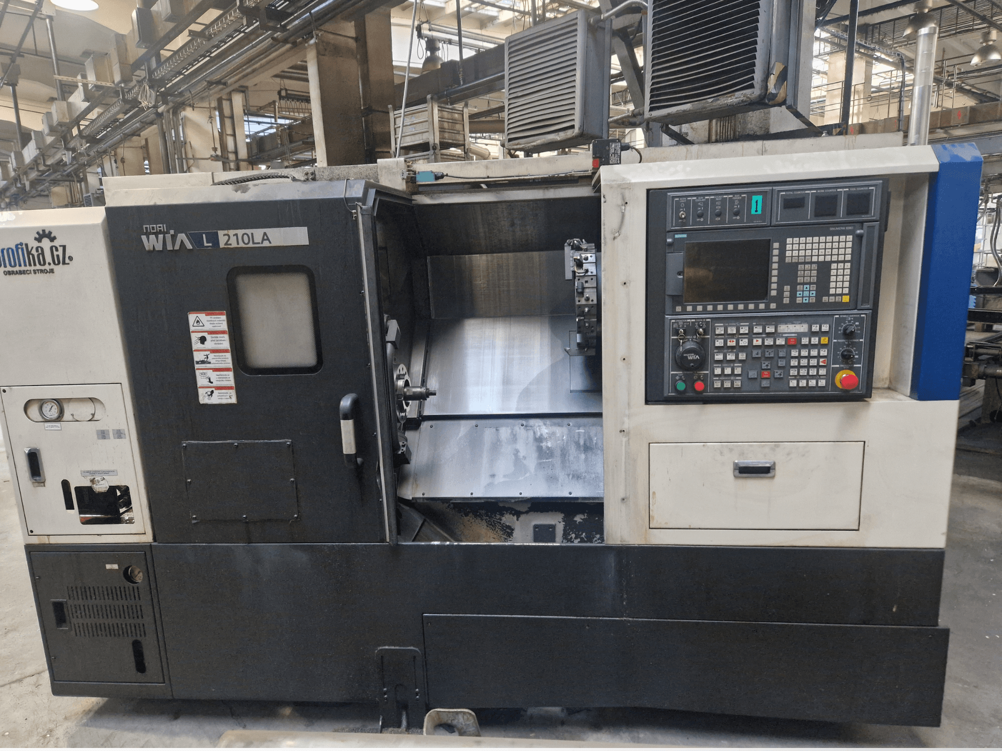 Máquina de torno CNC WIA L210LA, vista frontal, com painel de controlo com botões, visor e uma área de maquinação visível.