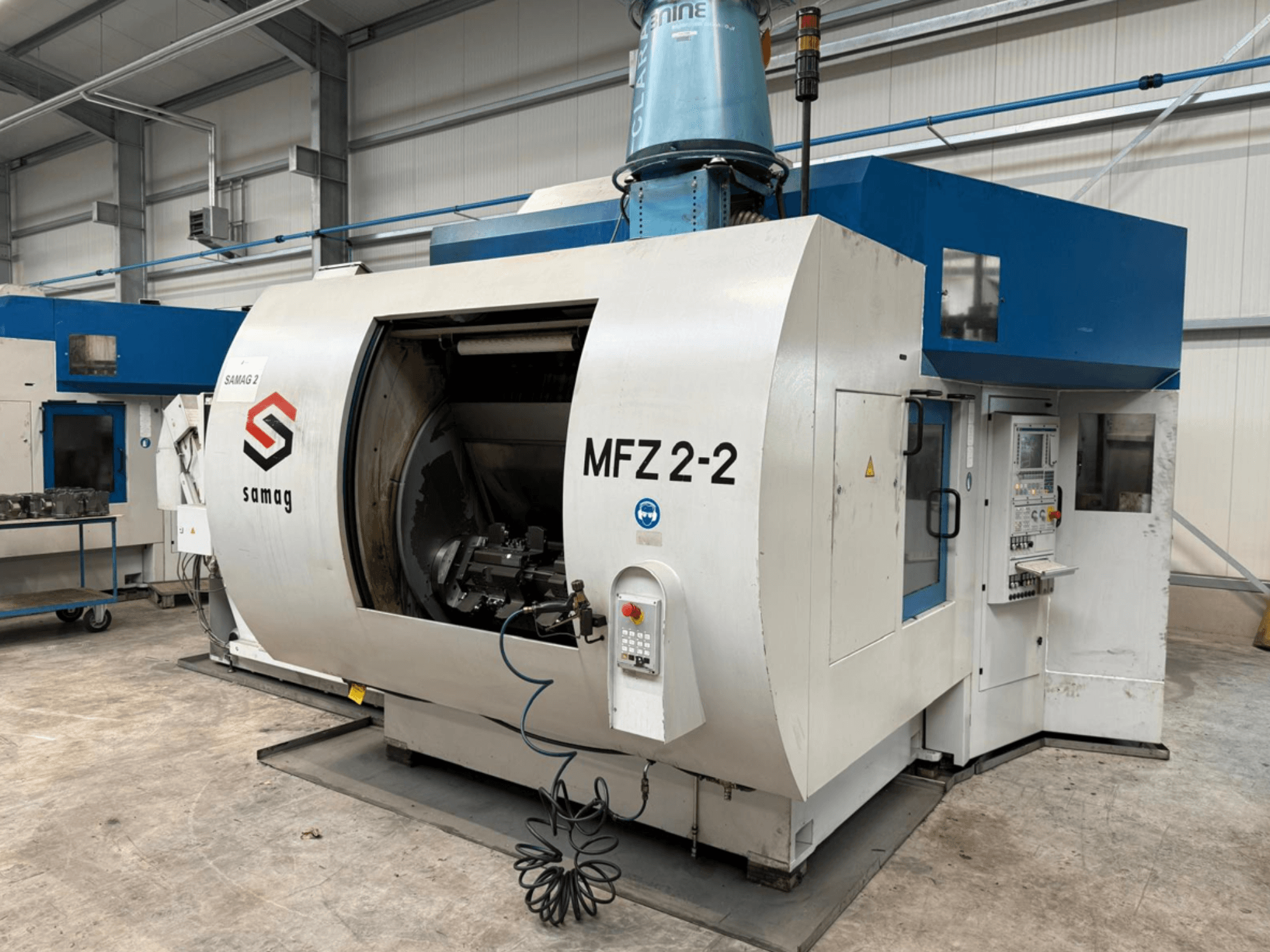 Fresadora Samag MFZ 2-2 em vista lateral, mostrando uma câmara grande e aberta e um painel de controlo com vários botões e manípulos.