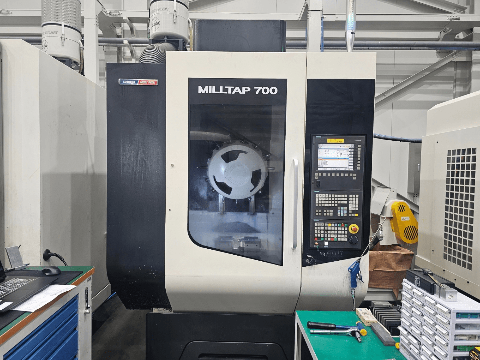 Centro de maquinagem vertical DMG MORI MILLTAP 700, vista frontal, mostrando detalhes do painel de controlo, do fuso e da área de trabalho.